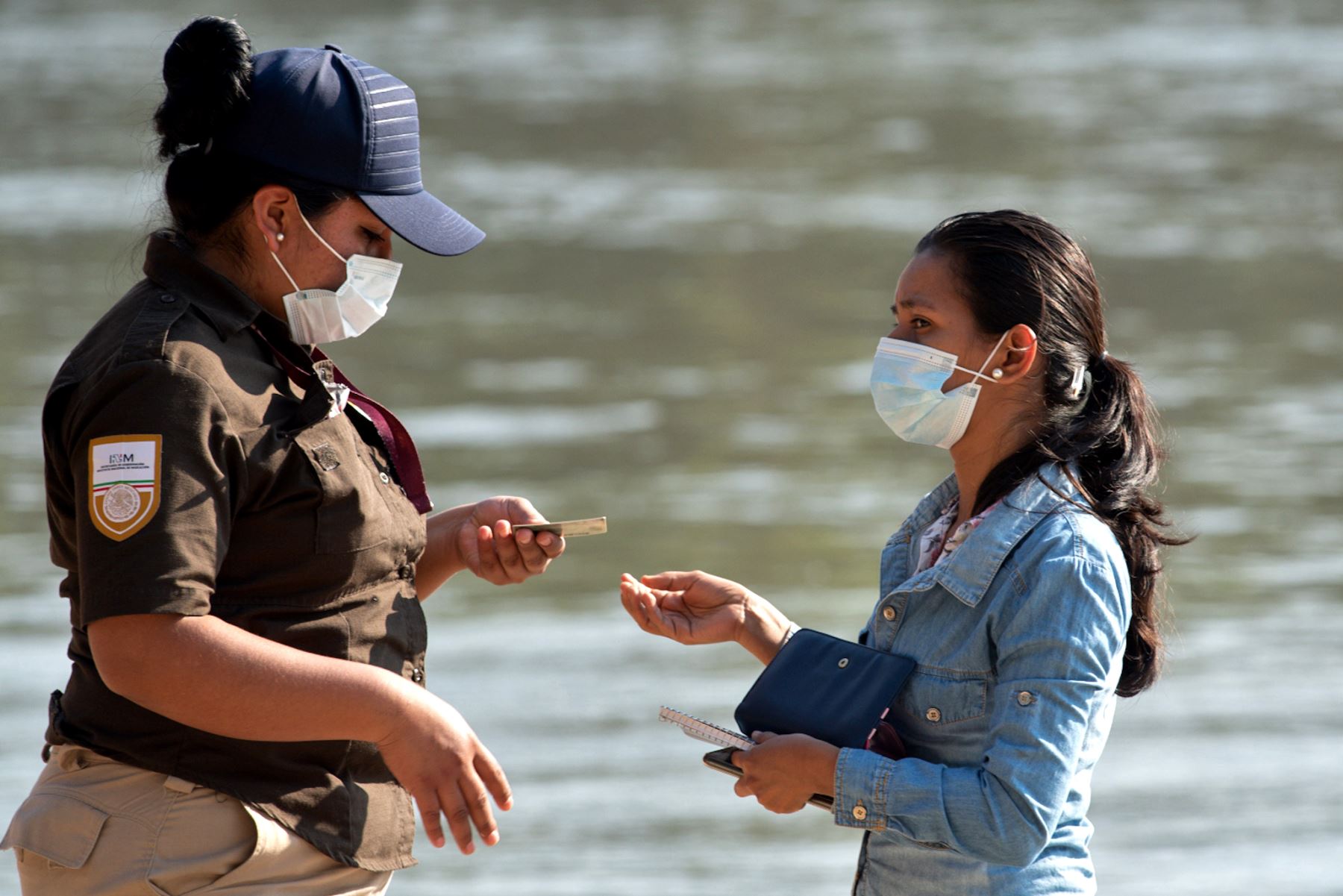Un funcionario del Instituto Nacional de Migración de México verifica el documento de una mujer antes de cruzar el río Suchiate desde Guatemala a Ciudad Hidalgo, México. Foto: AFP