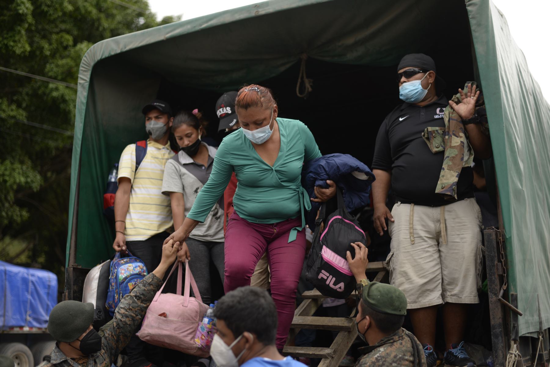 Los migrantes hondureños que regresan voluntariamente a Honduras son ayudados por soldados cuando bajan de un camión del ejército en El Florido, Chiquimula, Guatemala. Foto: AFP