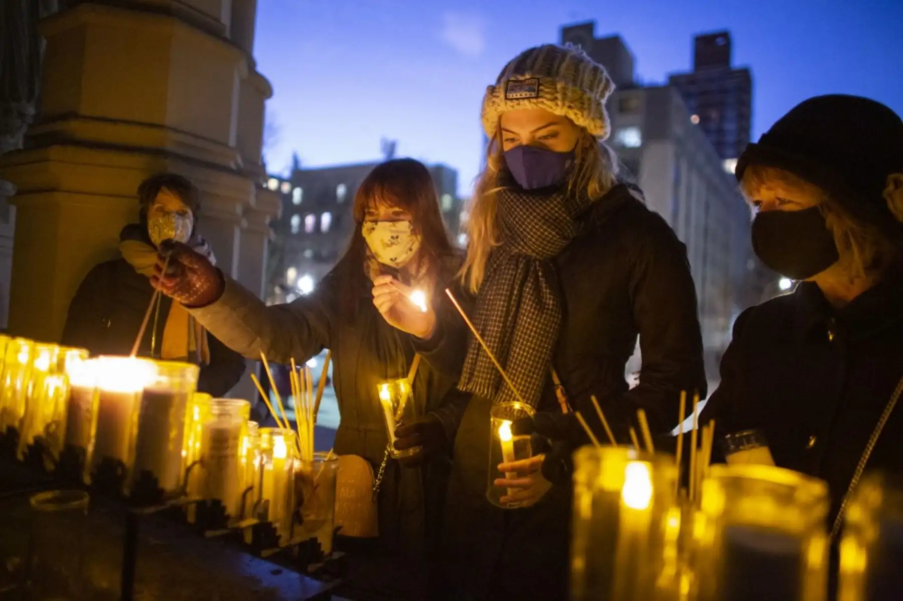 La gente enciende velas durante una "Vigilia de Unidad" antes de la 59a ceremonia inaugural del presidente electo Joe Biden y la vicepresidenta electa Kamala Harris, en la Iglesia Catedral de San Juan el Divino en Nueva York. Foto: AFP