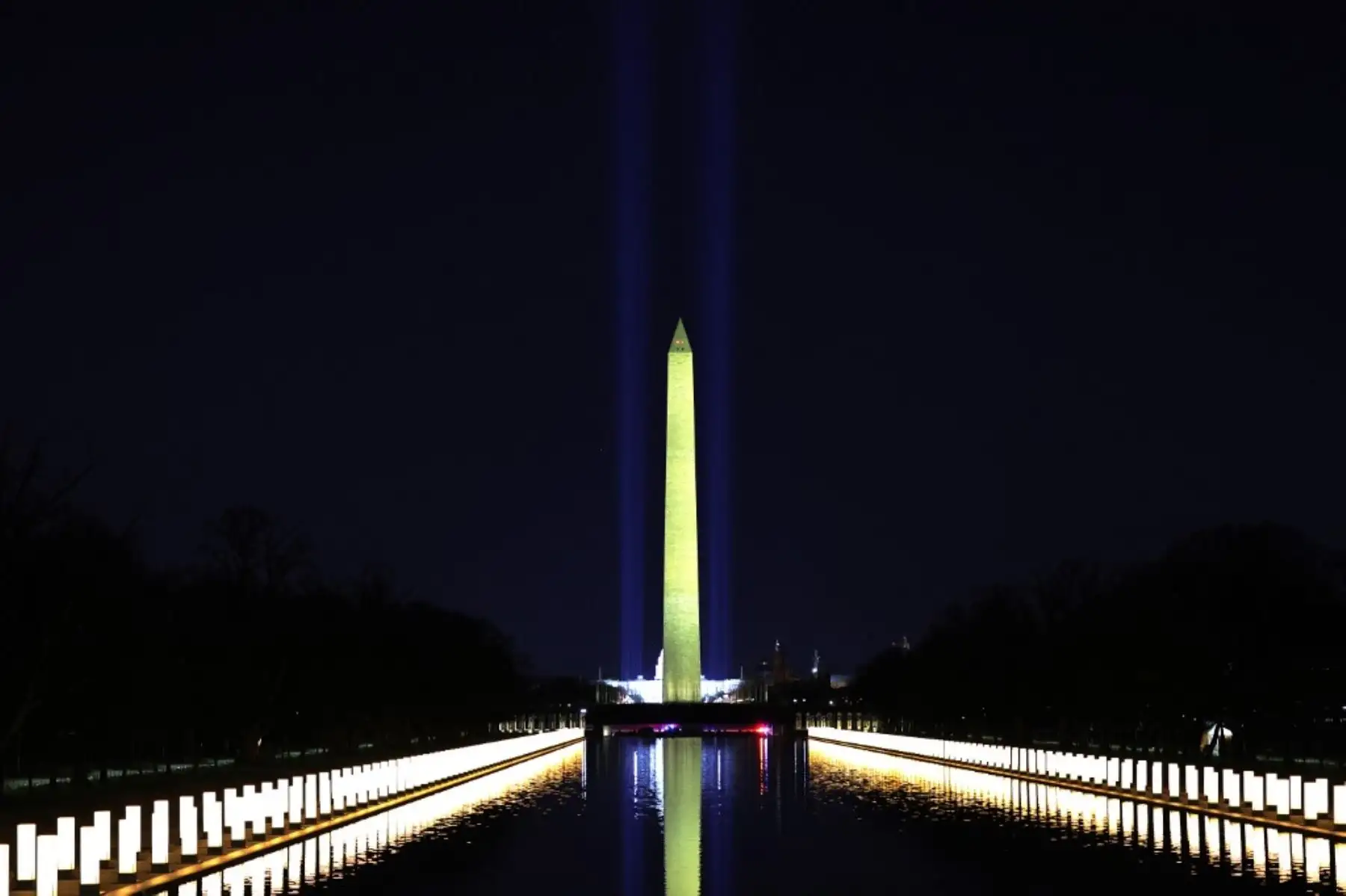 Las columnas que representan a las víctimas del coronavirus covid-19 se encienden mientras se exhiben a lo largo de los lados del Lincoln Memorial Reflecting Pool después de que el presidente electo Joe Biden y la vicepresidenta electa Kamala Harris asistan a un memorial en el víspera de la toma de posesión presidencial el 19 de enero de 2021 en Washington. Foto: AFP