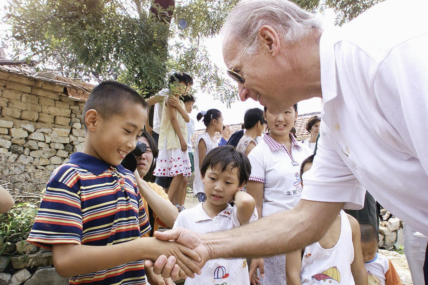 El presidente del Comité de Relaciones Exteriores del Senado de los Estados Unidos, Joseph Biden, le da la mano a Gao Shan, de nueve años, el niño que Biden proclamó como futuro presidente de China, durante una visita a la aldea de Yanzikou, al norte de Beijing, el 10 de agosoto del 2001. Foto: AFP