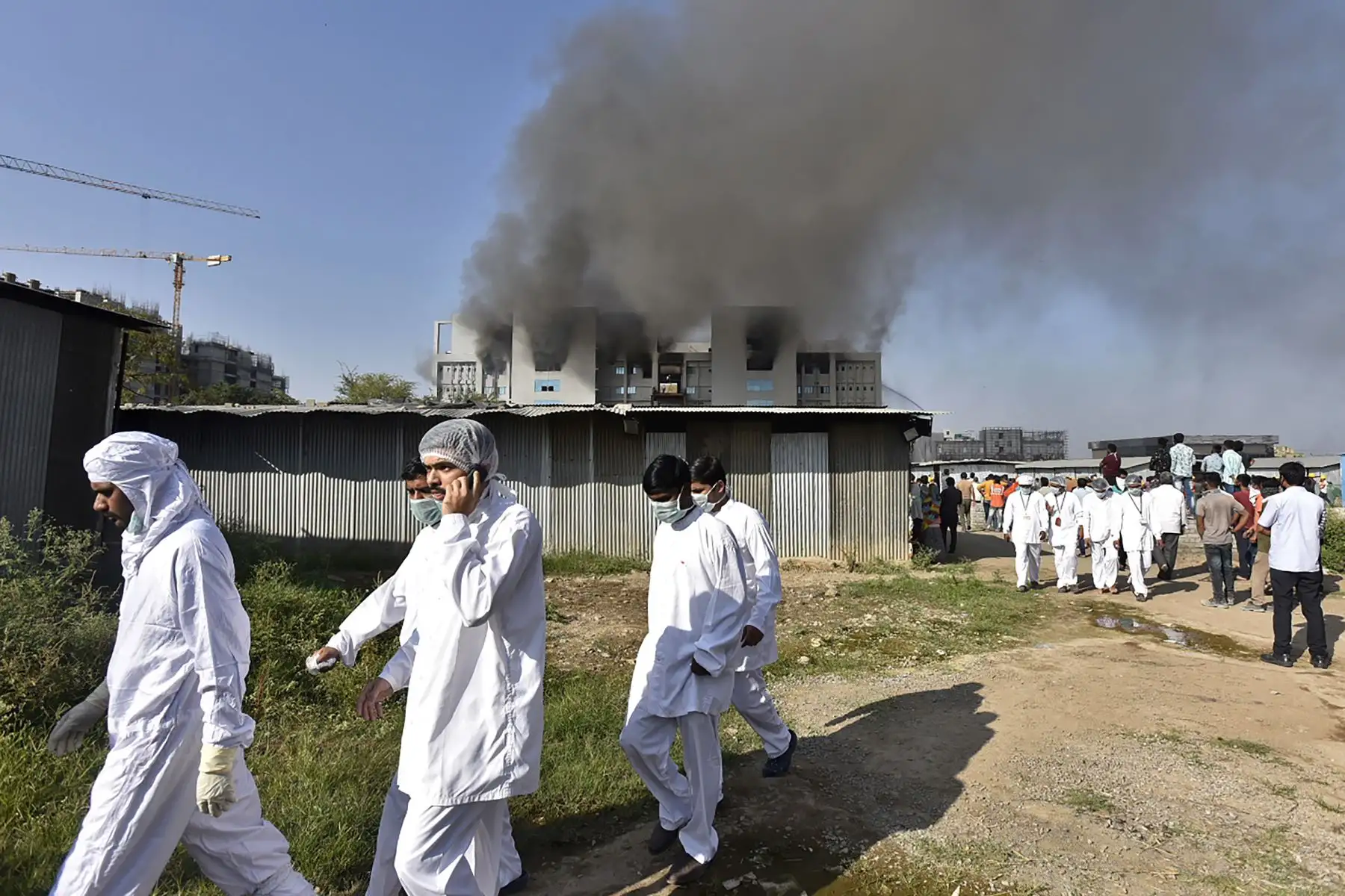 Los trabajadores con equipo de protección caminan después de que estalló un incendio en el Serum Institute de India en  el mayor fabricante de vacunas del mundo.
Foto: AFP