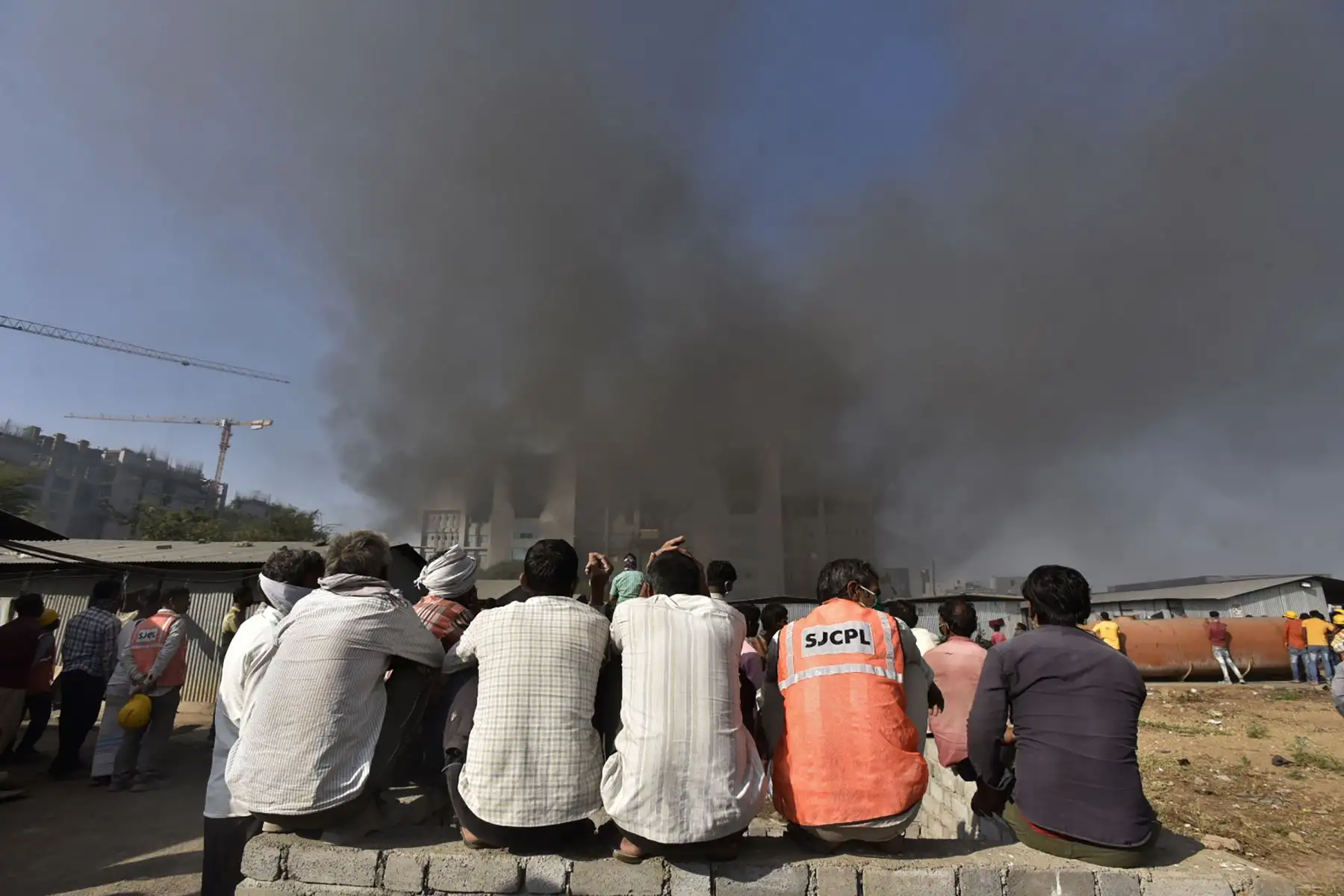 La gente observa cómo se eleva el humo después de que estalló un incendio  en el Serum Institute de India, el mayor fabricante mundial de vacunas, los medios dijeron que la producción de la vacuna contra el coronavirus  no se vio afectada.
AFP