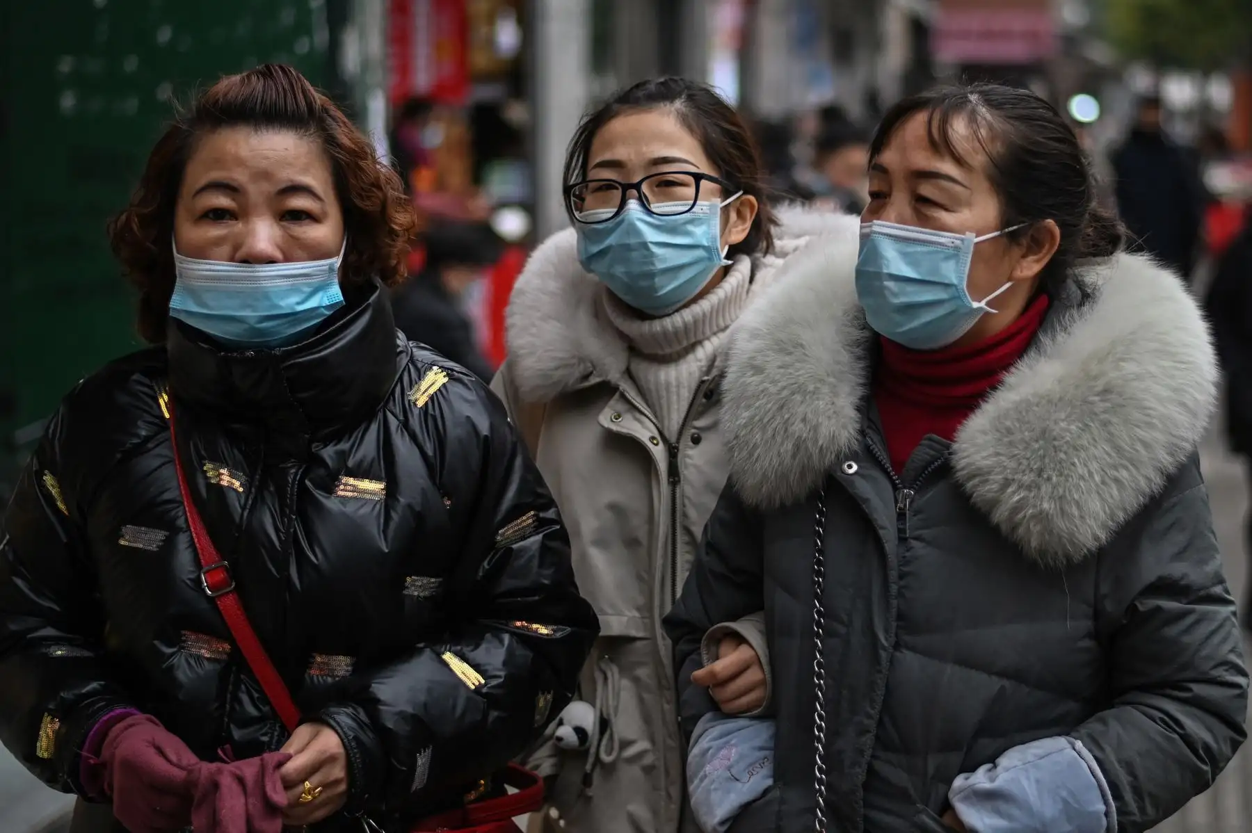 Los peatones con máscaras faciales como medida preventiva contra el coronavirus Covid-19 caminan en una calle de Wuhan. Foto: AFP