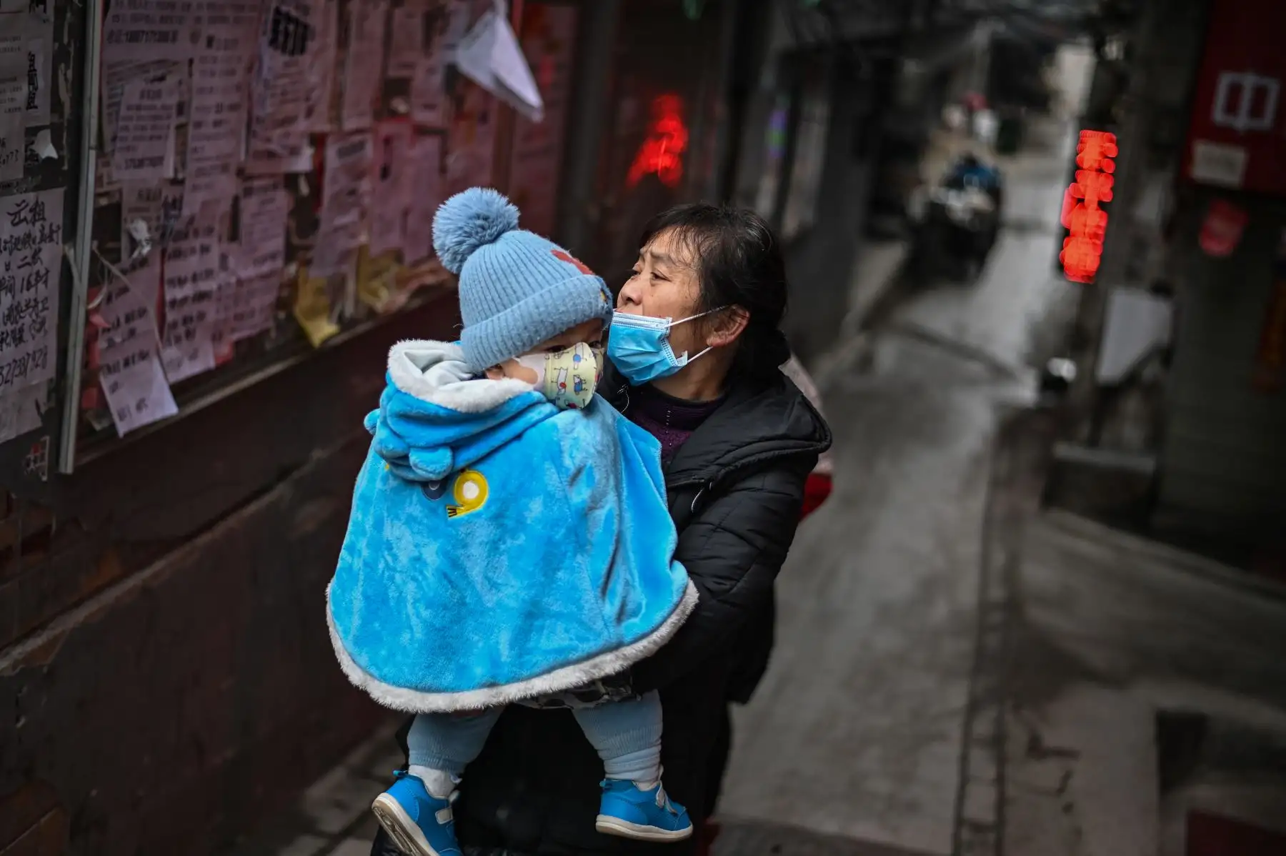 Una mujer que usa una mascarilla como medida preventiva contra el coronavirus Covid-19 camina por un camino con un bebé en brazos en Wuhan. Foto: AFP