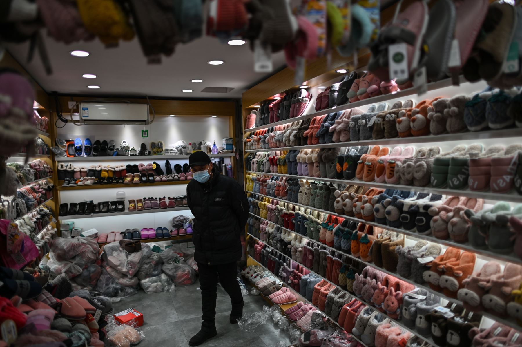 Un vendedor que usa una mascarilla como medida preventiva contra el coronavirus Covid-19 espera a los clientes en una tienda de zapatillas en Wuhan. Foto: AFP