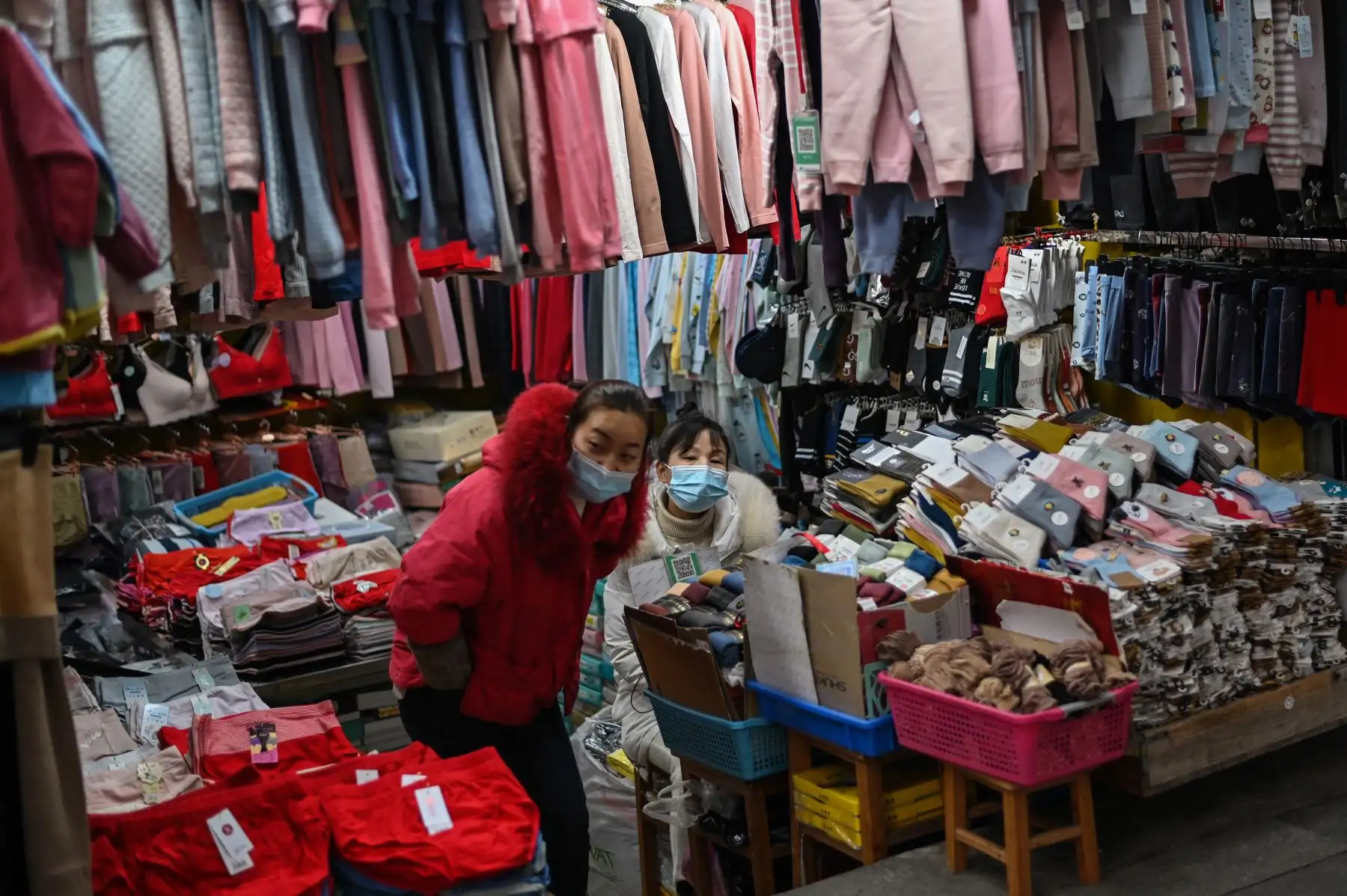 Los vendedores que usan máscaras faciales como medida preventiva contra el coronavirus Covid-19 esperan a los clientes en una tienda en Wuhan. Foto: AFP