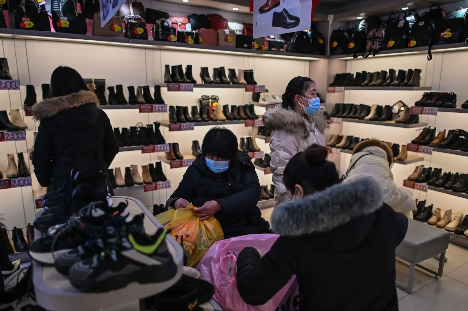 Personas que usan mascarillas como medida preventiva contra el coronavirus Covid-19 visitan una zapatería en Wuhan. Foto: AFP