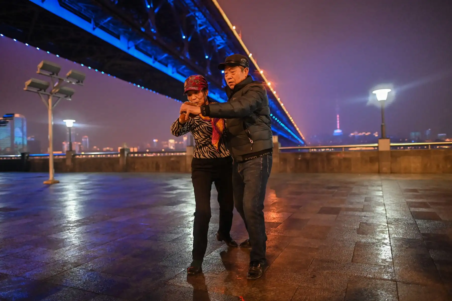 Una pareja baila junto al puente de Wuhan que cruza el río Yangtze en Wuhan, provincia de Hubei, en el centro de China. Foto: AFP