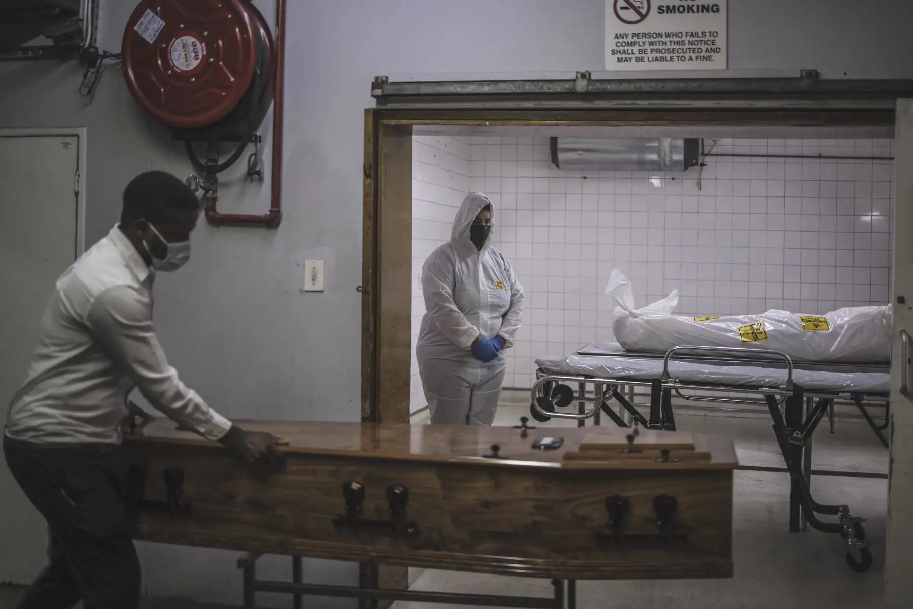Un asistente de la morgue en la sucursal de Pretoria de la compañía sudafricana de servicios funerarios y de entierro Avbob permanece inmóvil junto al cuerpo de un paciente fallecido por enfermedades relacionadas con covid-19 mientras un ataúd trajo antes de su entierro.
Foto: AFP