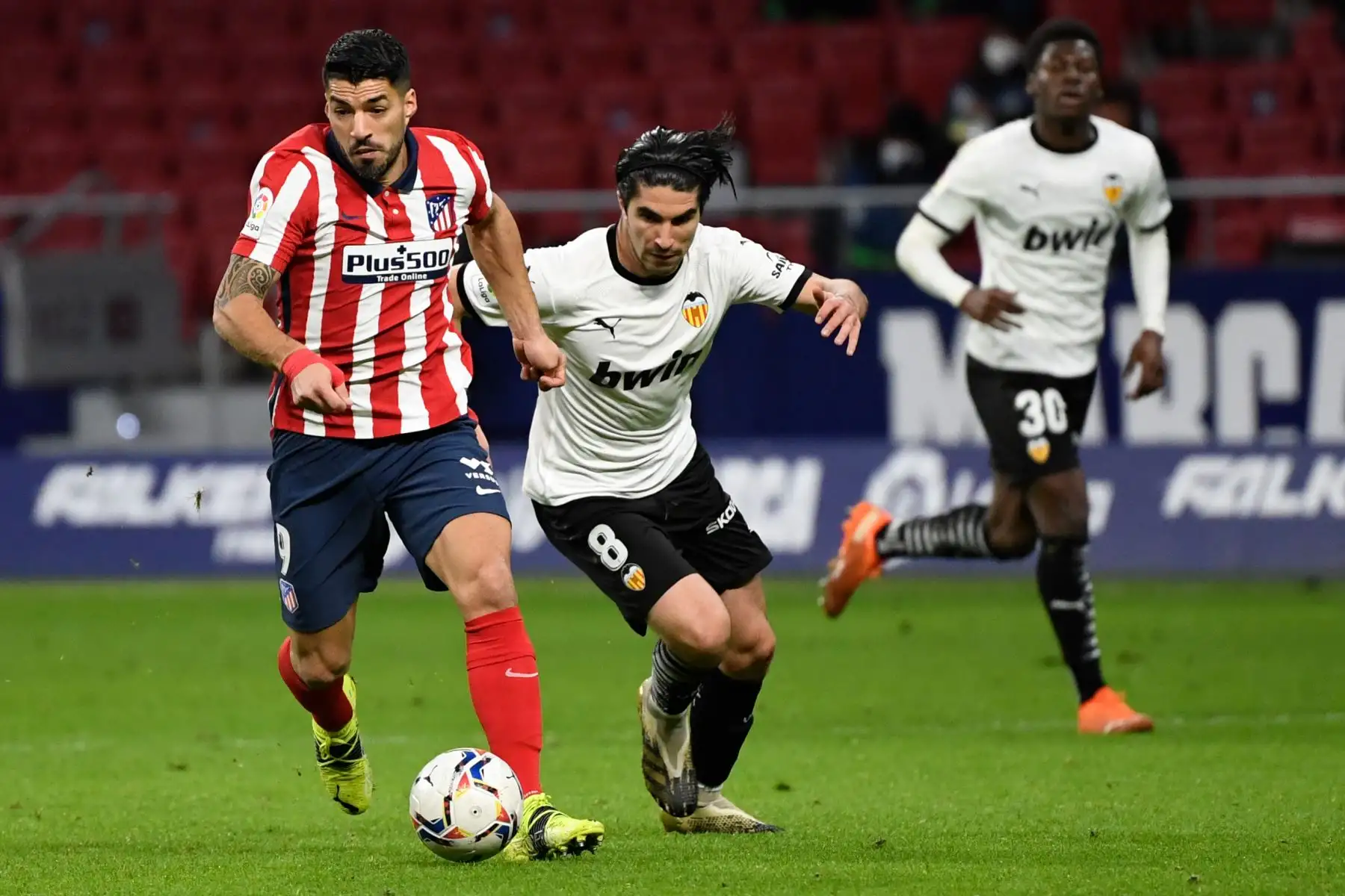 El delantero uruguayo del Atlético de Madrid Luis Suárez compite con el centrocampista español del Valencia Carlos Soler durante el partido de fútbol de la liga española entre el Club Atlético de Madrid y el Valencia CF en el estadio Wanda Metropolitano de Madrid el 24 de enero de 2021. Foto: AFP