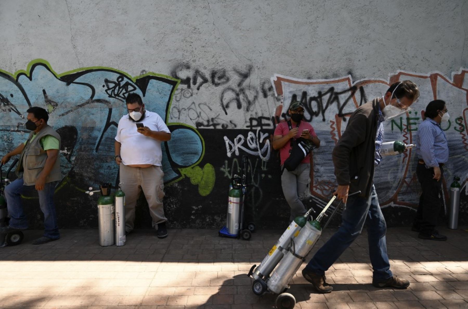 Personas hacen fila para rellenar los tanques de oxígeno en la Compañía Infra Medica en la Ciudad de México. Foto: AFP