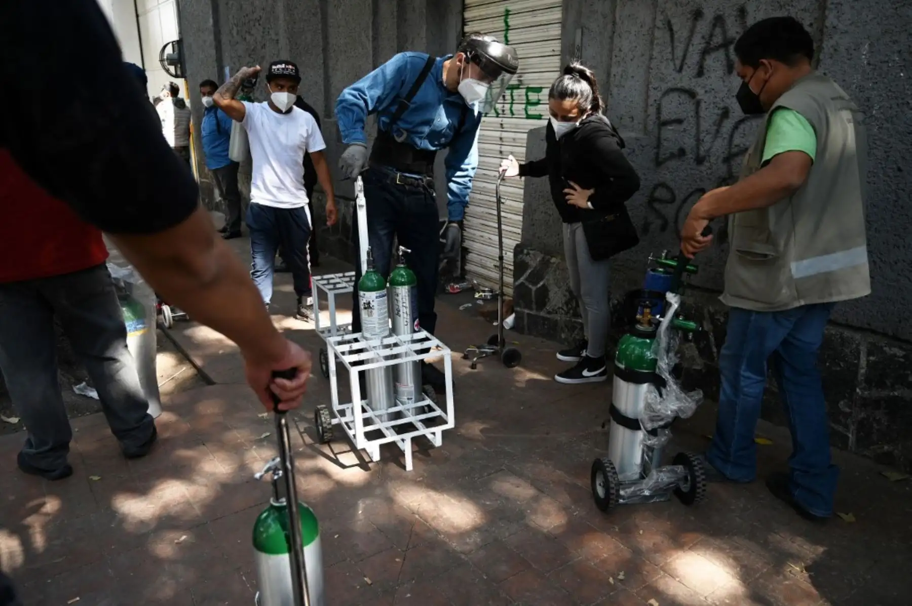 Un empleado de la Compañía Infra Medica entrega tanques de oxígeno rellenados a personas en una cola en la Ciudad de México. Foto: AFP