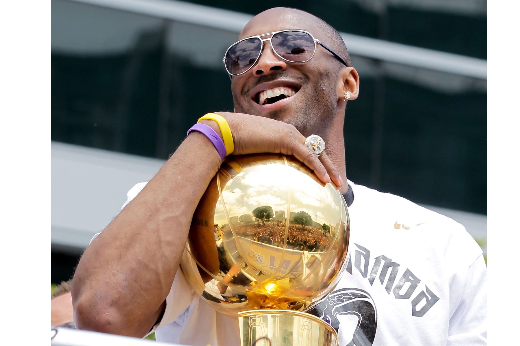El guardia de Los Angeles Lakers, Kobe Bryant, se ríe con el trofeo del campeonato mientras participa en el desfile de la victoria del equipo campeón de baloncesto de la NBA el 21 de junio de 2010 en Los Ángeles, California. Foto: AFP
