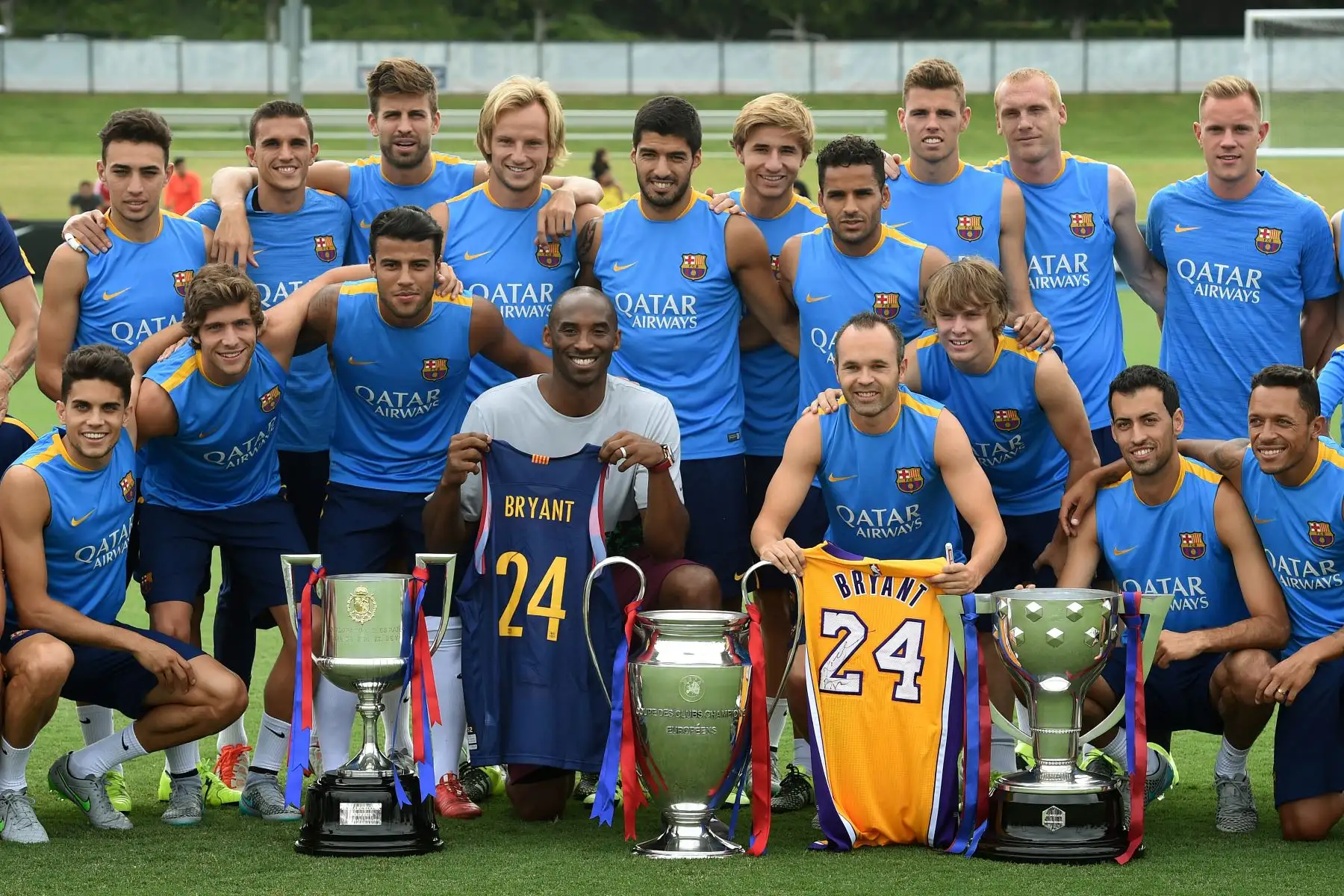 La estrella del baloncesto de Los Angeles Lakers, Kobe Bryant, y el capitán del equipo de Barcelona, ​​Andrés Iniesta Luján, posan con otros miembros del equipo de fútbol del FC Barcelona antes de una sesión de entrenamiento en el estadio StarHub de Carson, California, el 20 de julio de 2015. Foto: AFP