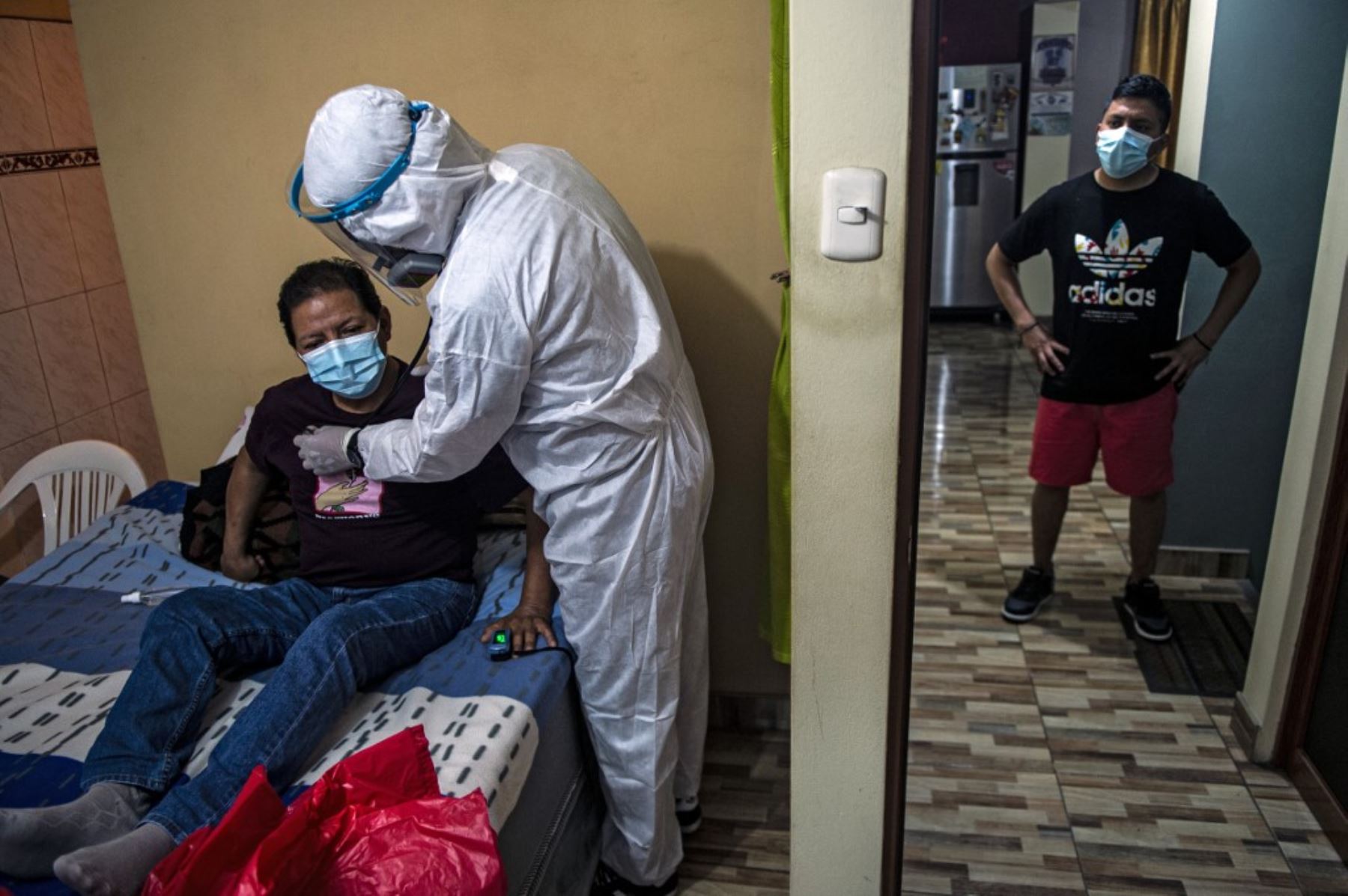 Un paciente de covid-19 es revisado por un médico durante una visita a su casa en las afueras del este de Lima, el 21 de enero de 2021, en medio de la pandemia del nuevo coronavirus. Foto: AFP