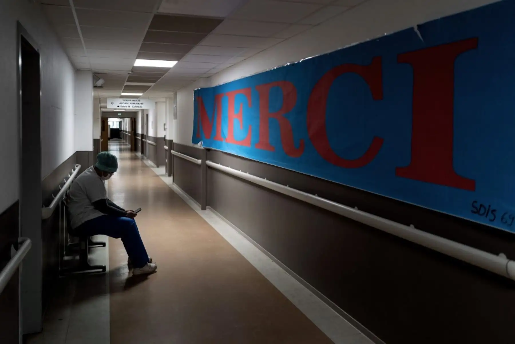Un empleado del hospital de Lyon-Sud espera en un pasillo, junto a un cartel escrito «Gracias», en la unidad de cuidados intensivos de Pierre-Benite. Foto: AFP