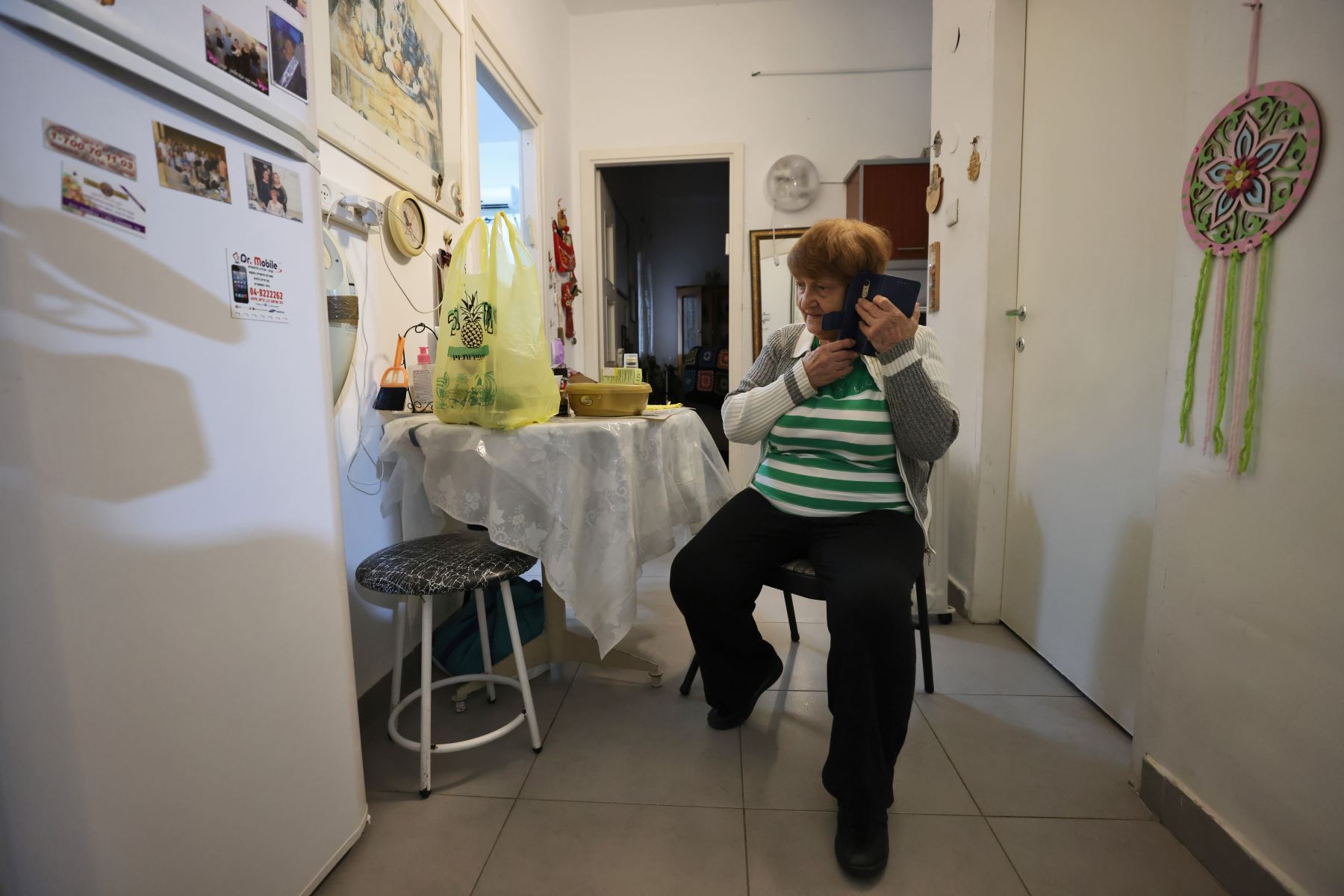 La sobreviviente del Holocausto Haya Caspi, de 88 años, habla por teléfono después de recibir un paquete de comida de un voluntario en las instalaciones de la fundación israelí Yad Ezer La-Haver. Foto: AFP