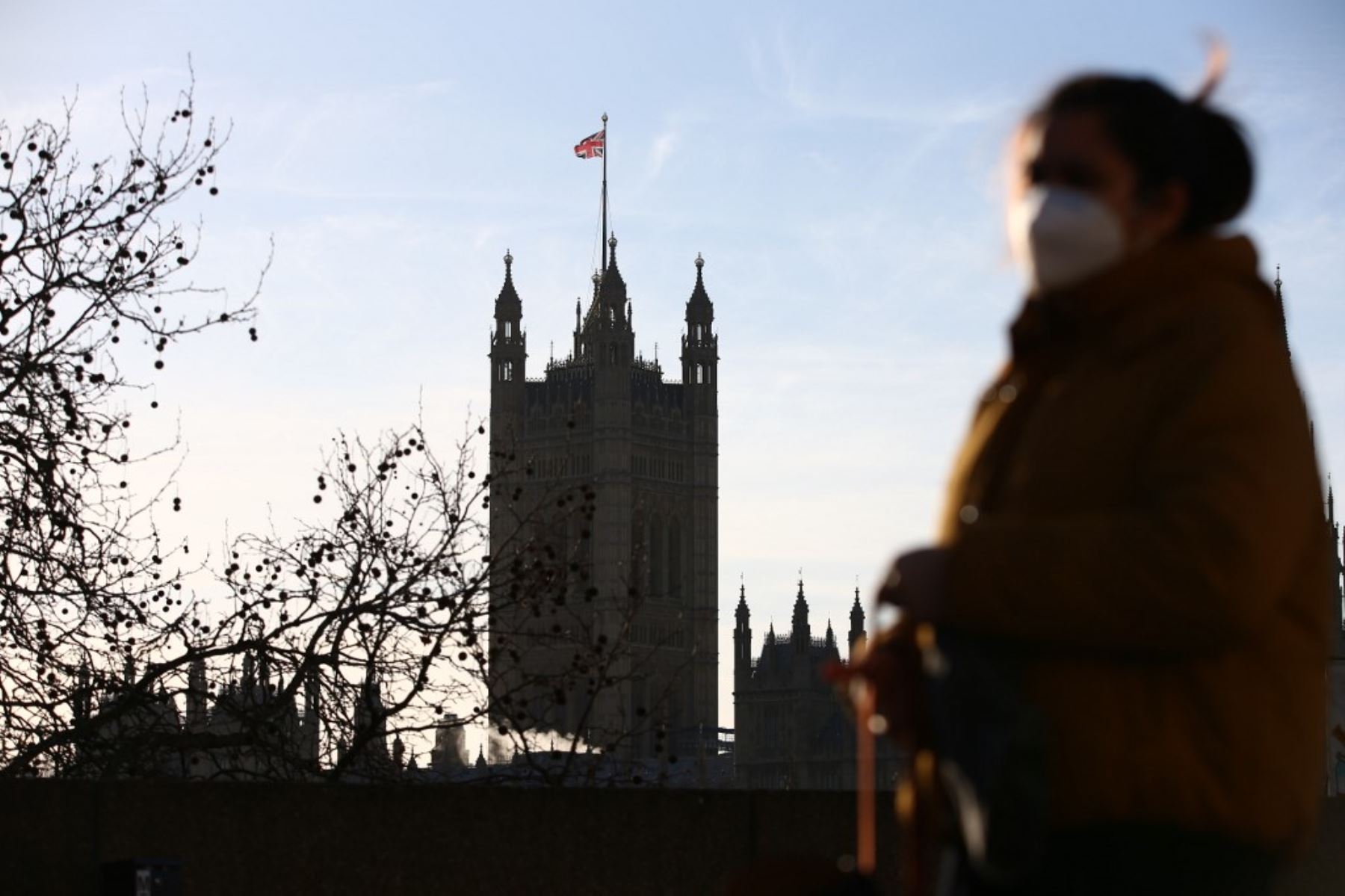 Un peatón con una máscara facial debido a la pandemia de Covid-19 camina por el centro de Londres con las Casas del Parlamento al fondo el 25 de enero de 2021. Foto: AFP