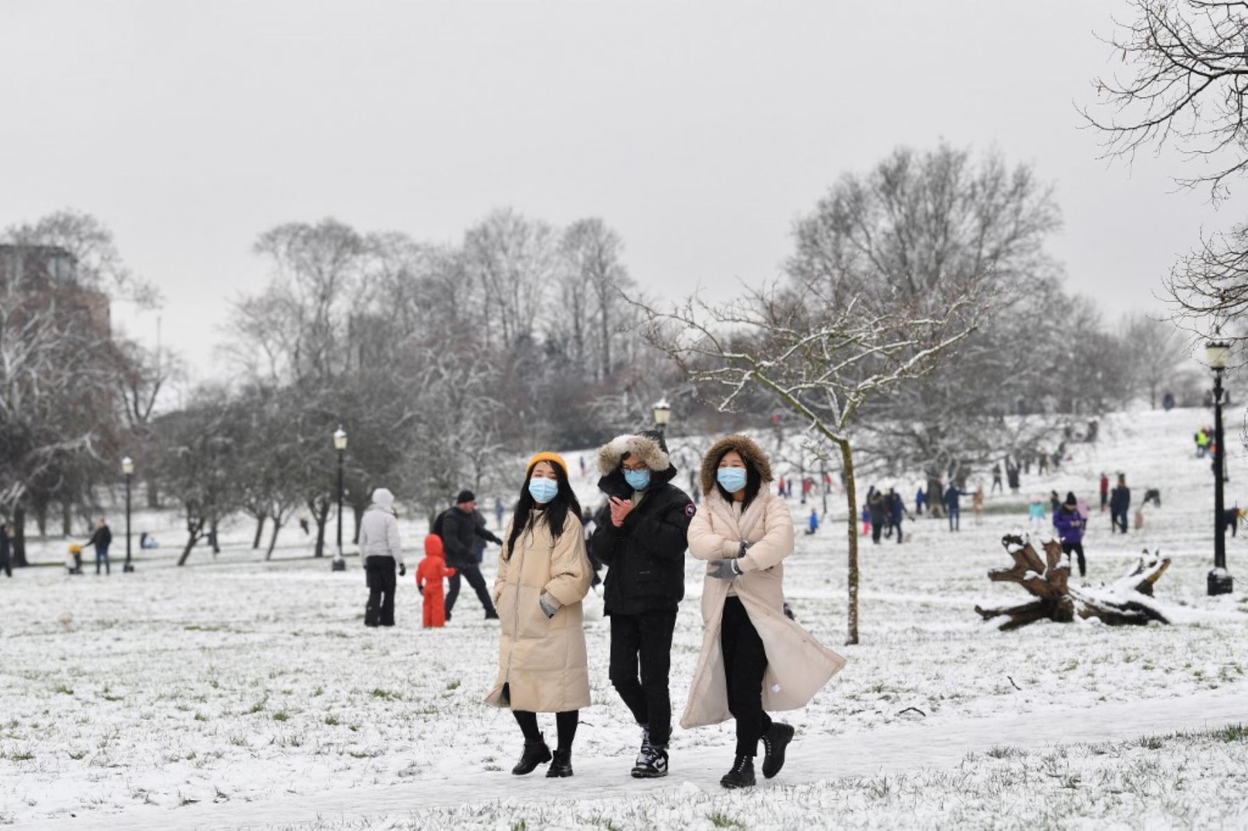 Las personas que usan protectores faciales para combatir la propagación del coronavirus, caminan en la nieve en Primrose Hill en Londres. Foto: AFP