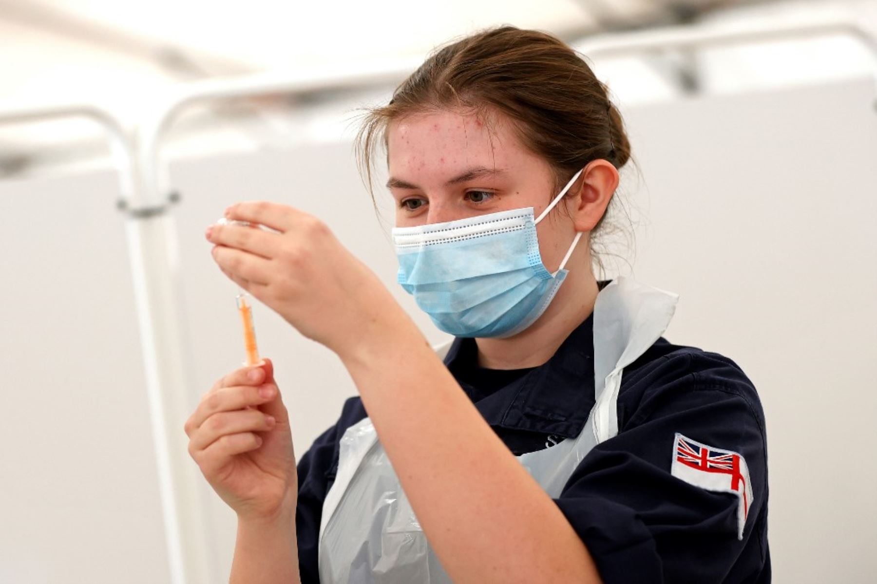 Los médicos de la Royal Navy preparan jeringas antes de administrar inyecciones de la vacuna Oxford / AstraZeneca Covid-19 a los miembros del público en un centro de vacunación establecido en el hipódromo de Bath en Bath, suroeste de Inglaterra. Foto: AFP