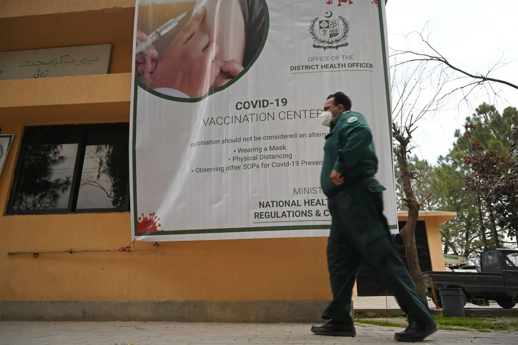 Un trabajador de la salud pasa junto a una pancarta de concientización sobre el covid-19 instalada en un centro de vacunación en Islamabad, Pakistán.
Foto: AFP