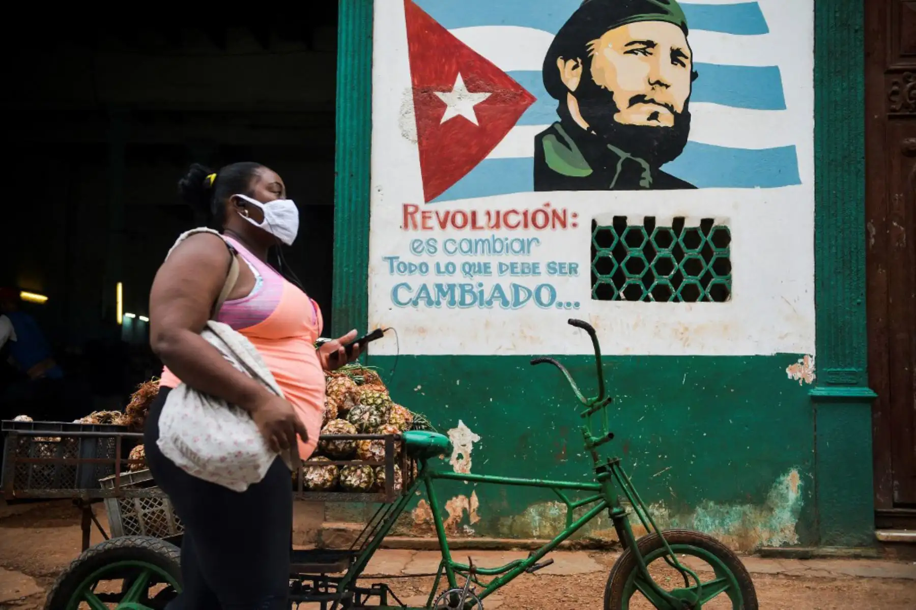 Una mujer con mascarilla camina cerca de un cartel que representa al fallecido líder cubano Fidel Castro por una calle de La Habana. Investigadores cubanos se han centrado en la tarea de desarrollar la primera vacuna contra covid-19 concebida y producido en América Latina. Foto: AFP
