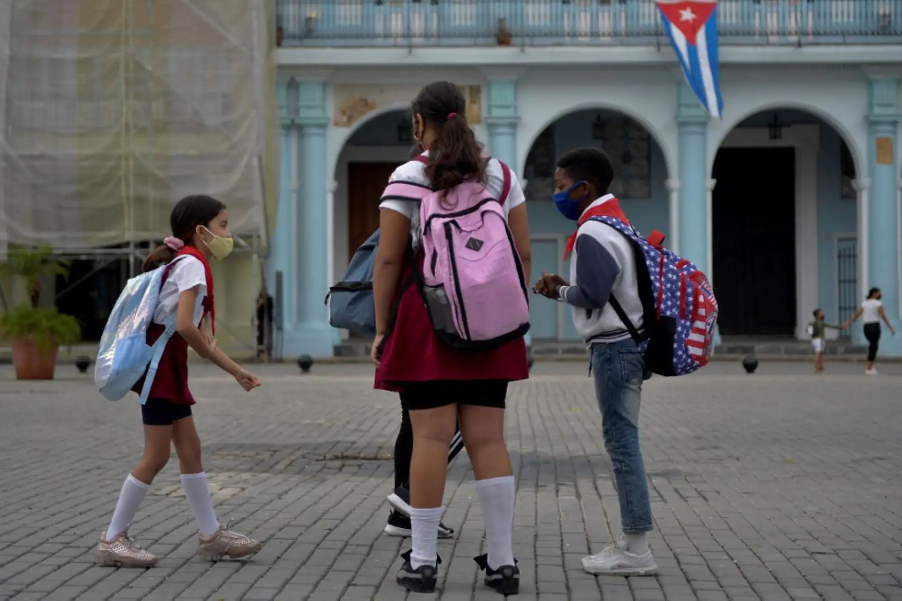 Niños con mascarilla esperan en un parque para ir a la escuela en La Habana. Foto: AFP