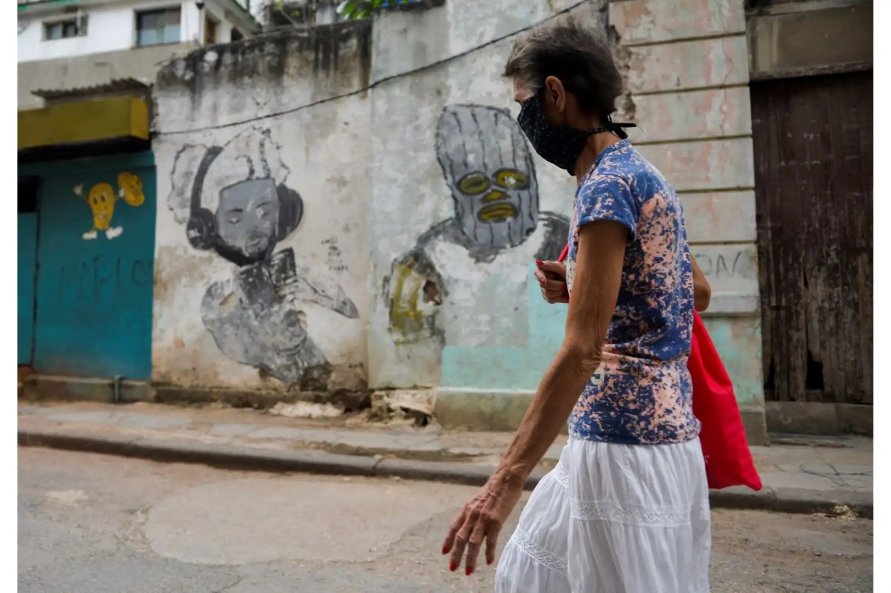 Una anciana con mascarilla camina cerca de un mural en La Habana. Investigadores cubanos se han centrado en la tarea de desarrollar la primera vacuna contra covid-19 concebida y producida en América Latina. Foto: AFP