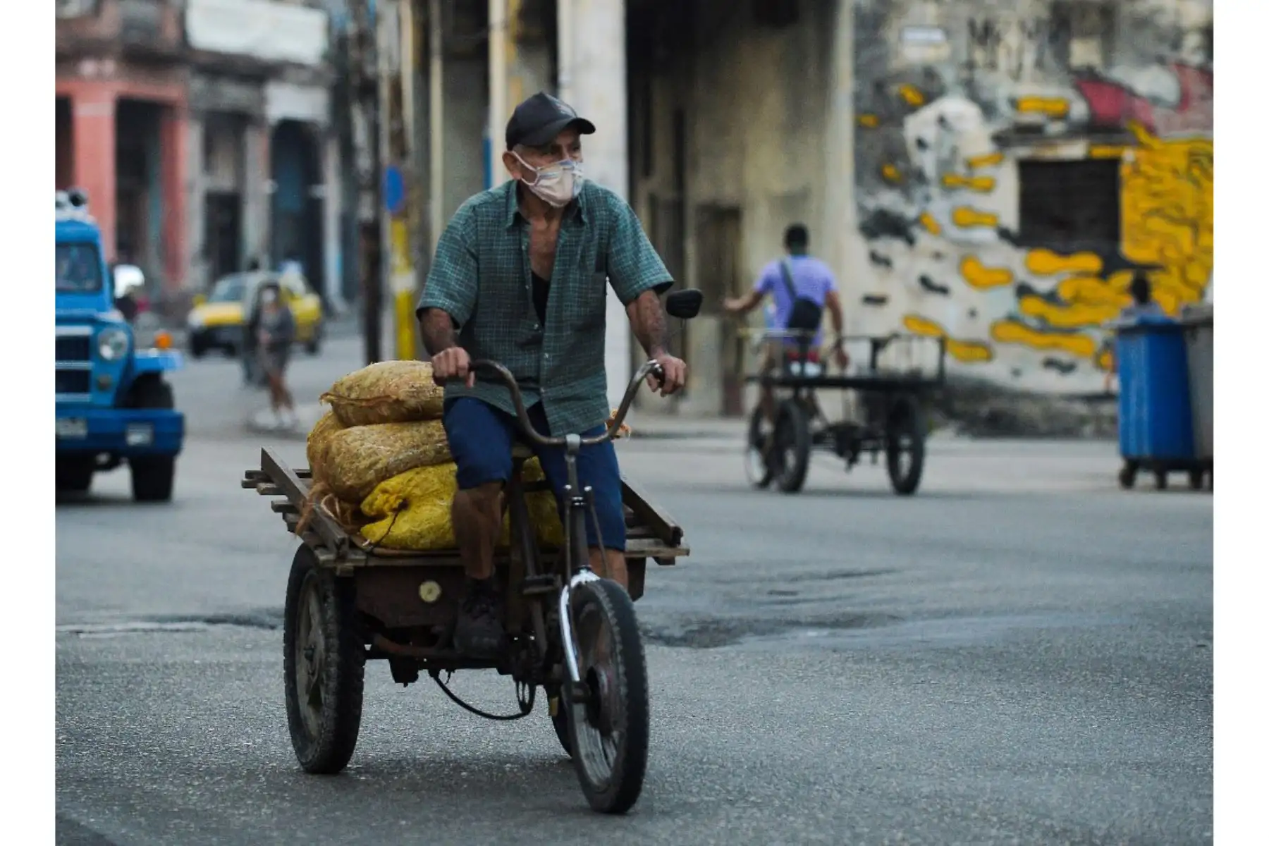 Un hombre con mascarilla transporta bolsas con verduras para la venta en La Habana. Investigadores cubanos se han centrado en la tarea de desarrollar la primera vacuna contra covid-19 concebida y producida en América Latina. Foto: AFP