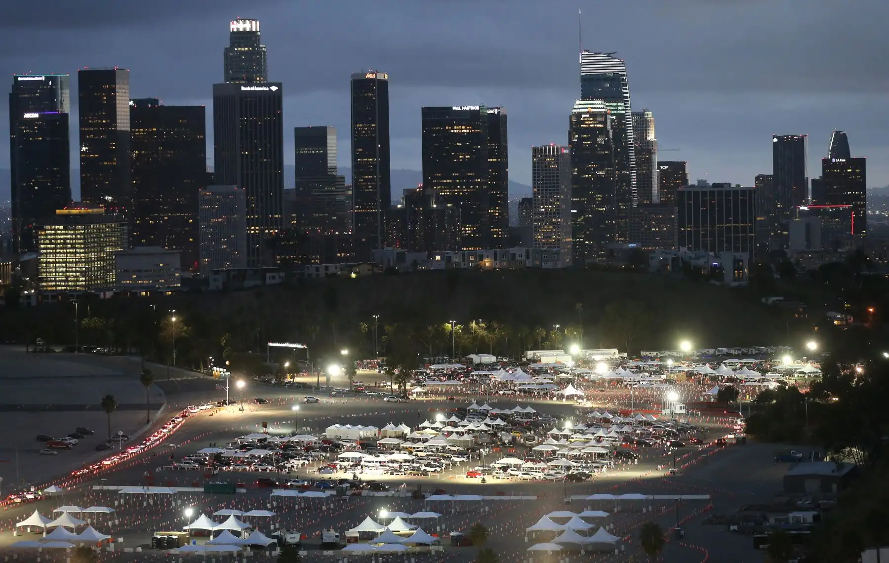 Autos hacen fila en un sitio de vacunación masiva COVID-19 en el Dodger Stadium, con el fondo de la ciudad de Los Ángeles, California.Foto: AFP