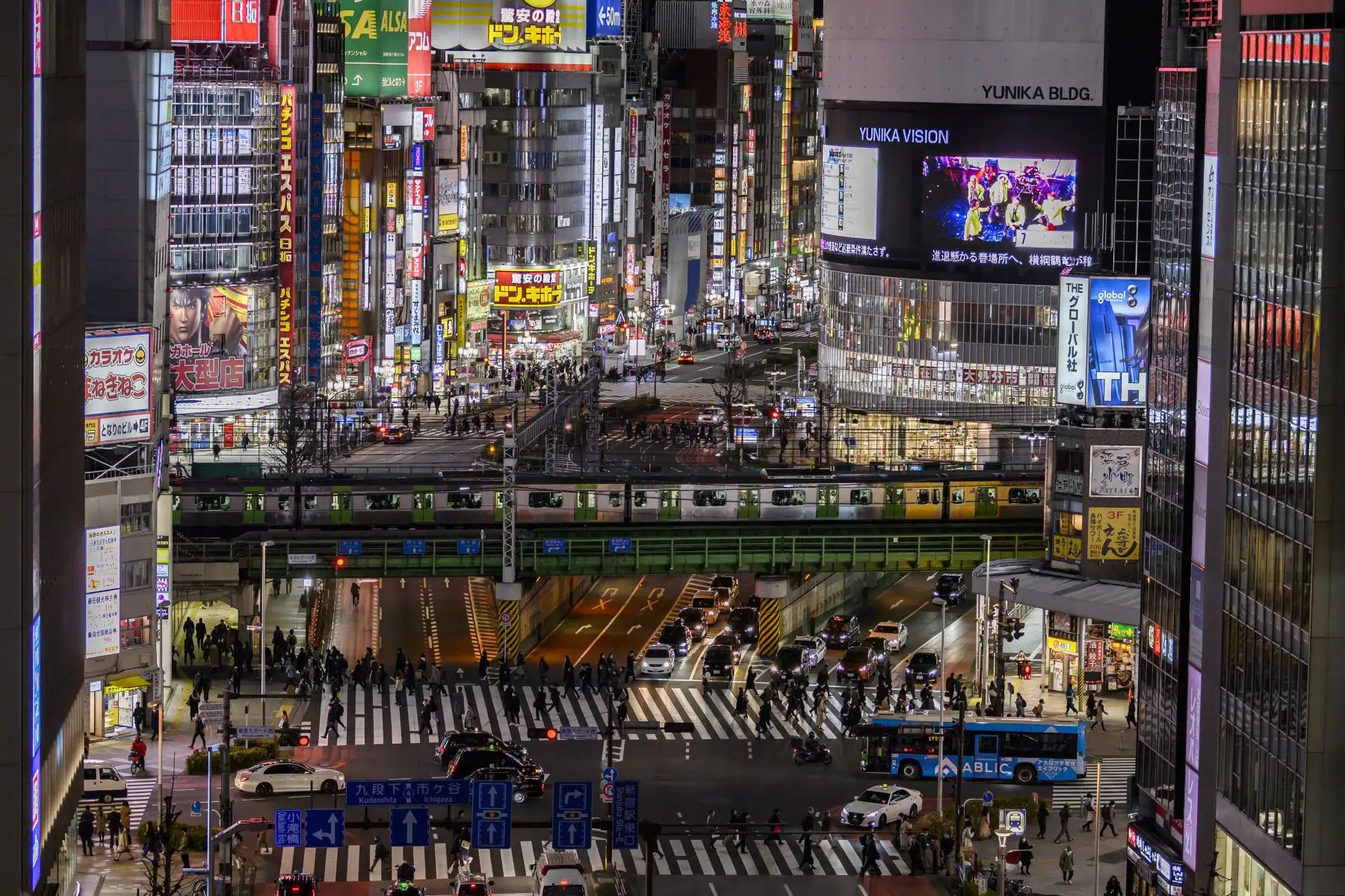 La gente usa los pasos de peatones mientras un tren viaja por el área de Shinjuku en Tokio. El gobierno de Japón aprobó extensión de un mes de su estado de emergencia por coronavirus. Foto: AFP