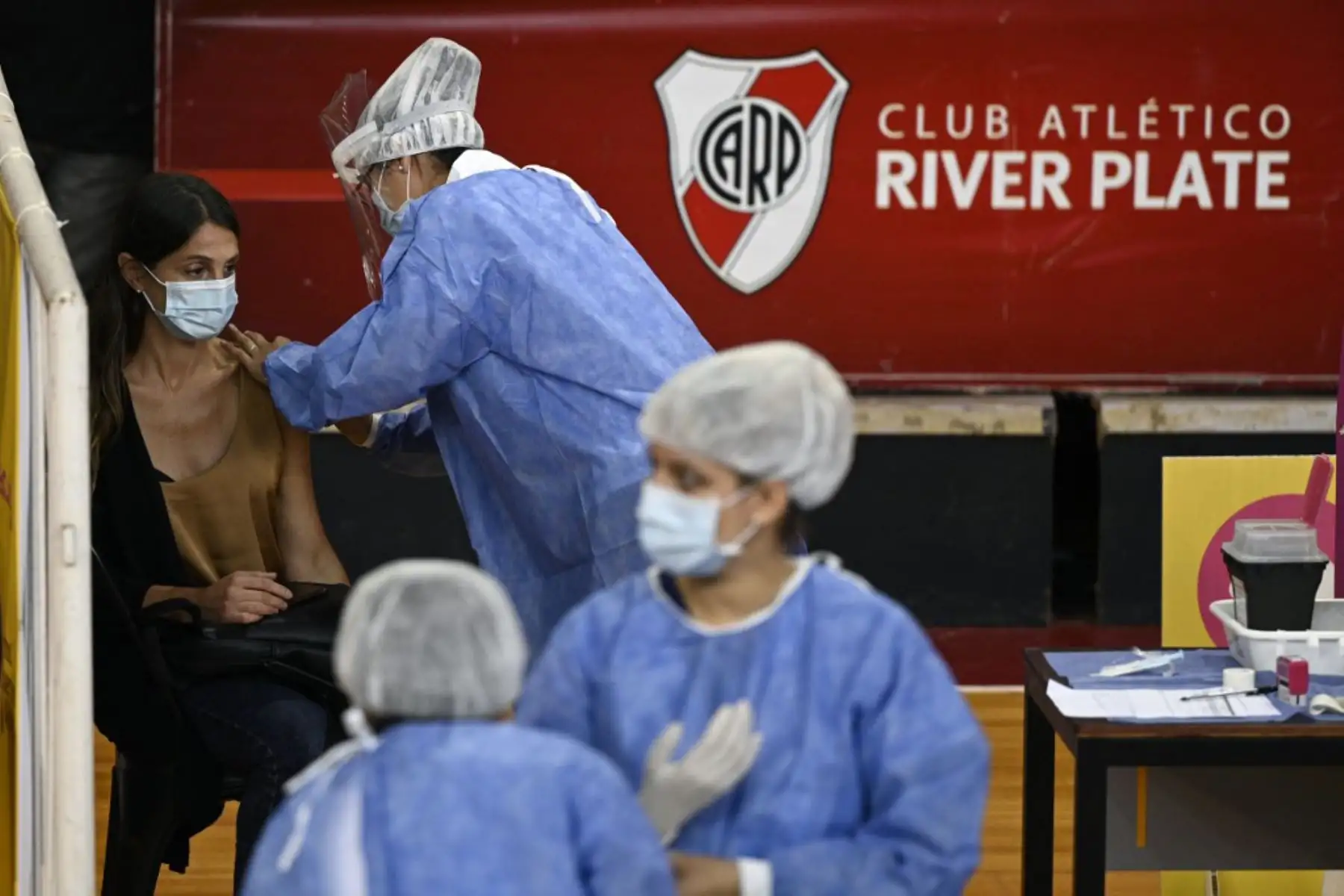 Un trabajador de la salud recibe una dosis de la vacuna Sputnik V contra el covid-19, en la cancha de baloncesto del club argentino River Plate, debajo de la tribuna del estadio Monumental, en Buenos Aires. Foto: AFP