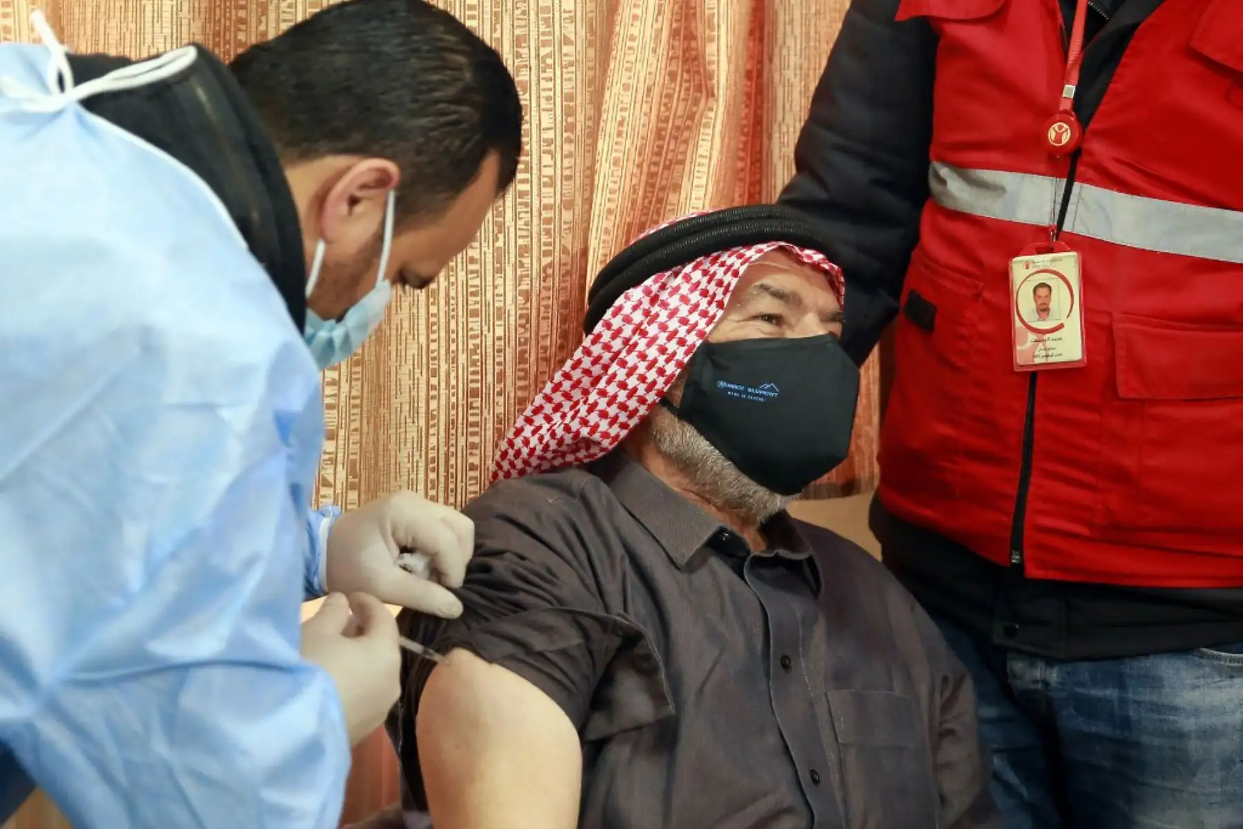 Un refugiado sirio con máscara y residente en Jordania recibe una dosis de vacunación contra la enfermedad por coronavirus covid-19 en un centro médico gubernamental en Mafraq, en el norte de Jordania. Foto: AFP