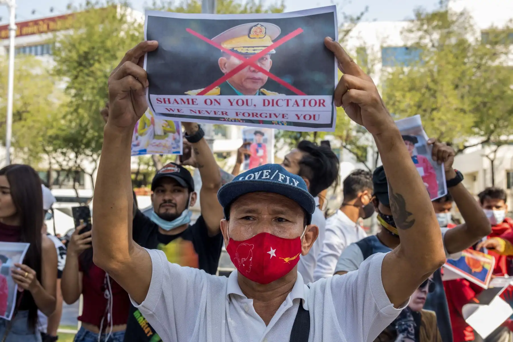 Un manifestante con una máscara facial de la Liga Nacional para la Democracia (LND) sostiene una imagen del jefe del ejército de Myanmar, general Min Aung Hlaing, frente al edificio de las Naciones Unidas en Bangkok, durante una manifestación contra el golpe militar en Myanmar. Foto: AFP