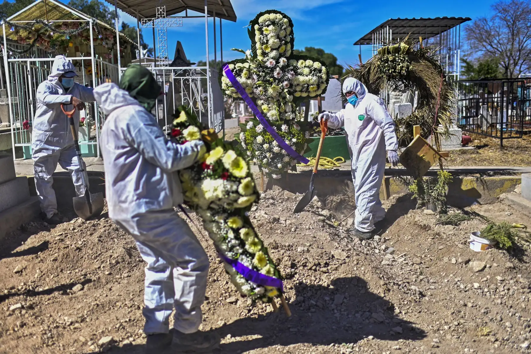 Sepultureros colocan flores en la tumba de una víctima del covid-19 en el Panteón Municipal de Ecatepec, Estado de México.

Foto: AFP