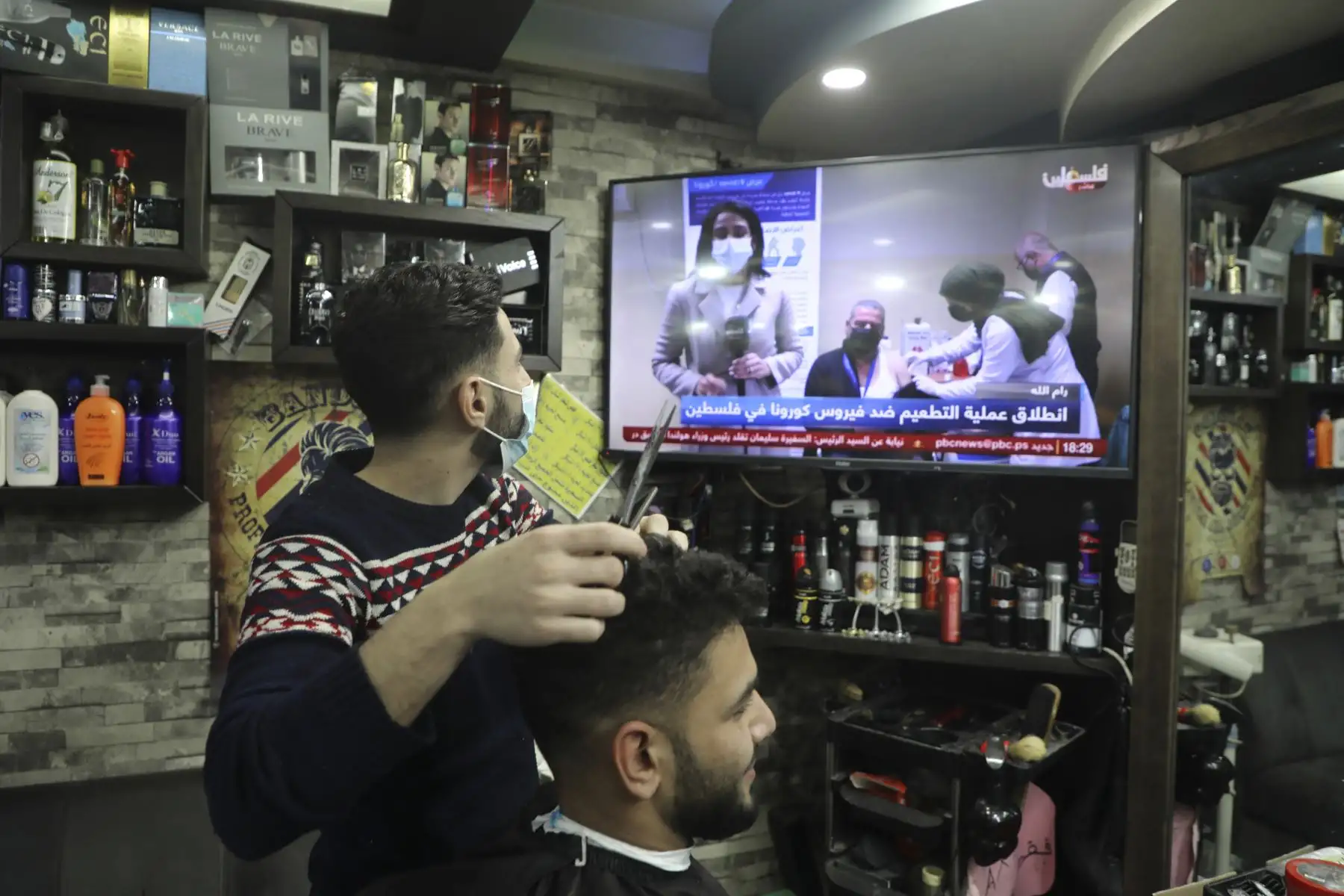 Un barbero mira las noticias en la ciudad ocupada de Naplusa en Cisjordania cuando la Autoridad Palestina comienza a vacunar a sus trabajadores de salud contra covid-19.

Foto: AFP