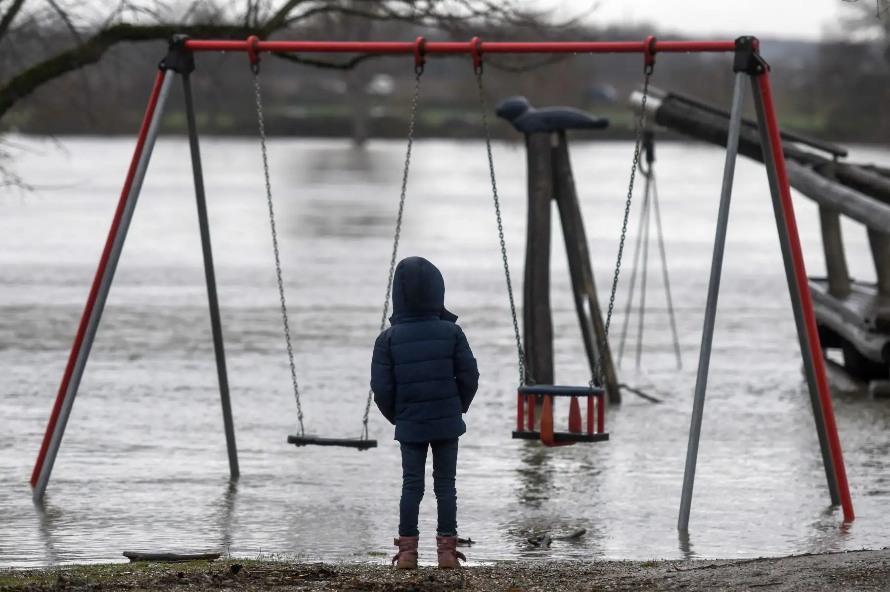 Un niño se encuentra en un parque infantil inundado por el río Rin en Mondorf, en el oeste de Alemania, después de que el río Rin se desbordara debido al derretimiento de la nieve y las precipitaciones persistentes.