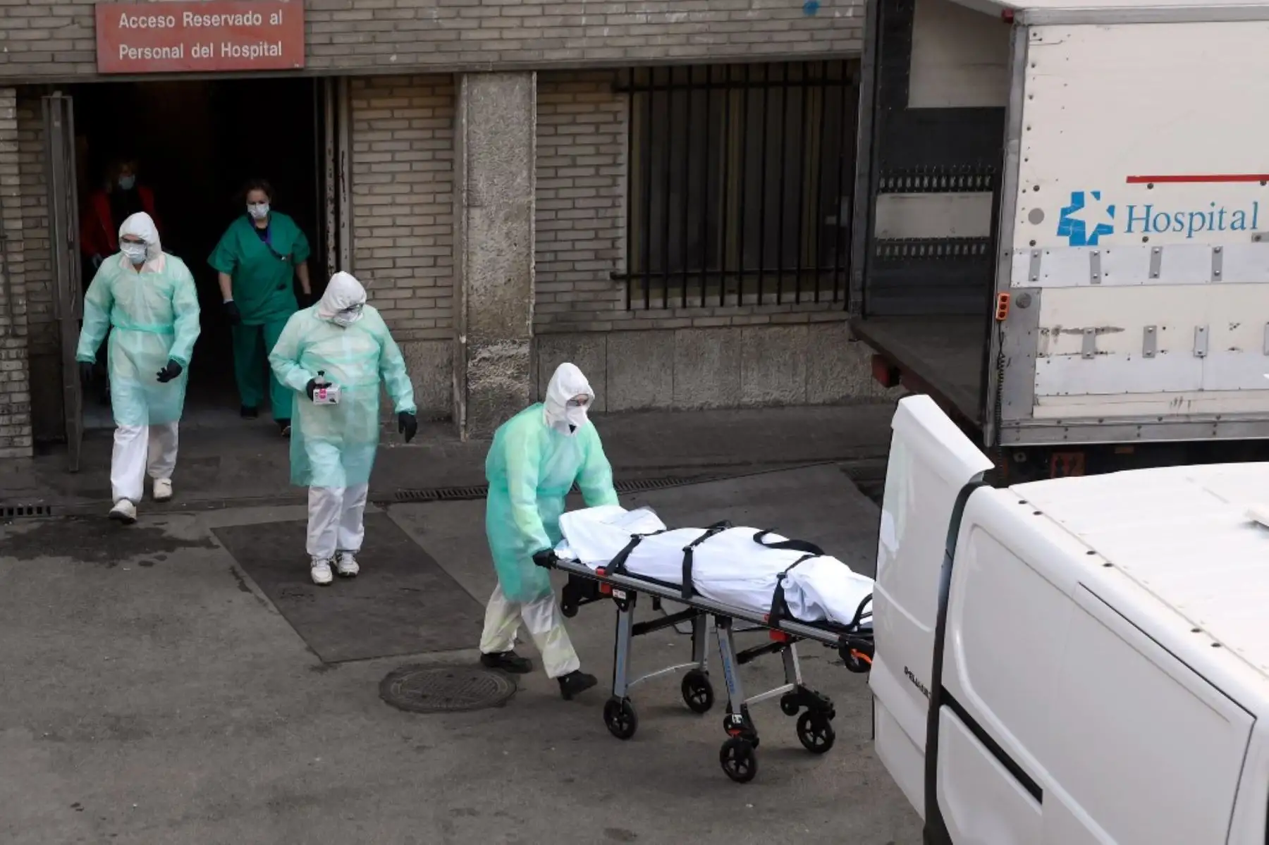 Un trabajador de la salud lleva un cuerpo en una camilla frente al hospital Gregorio Marañón en Madrid. Foto: AFP