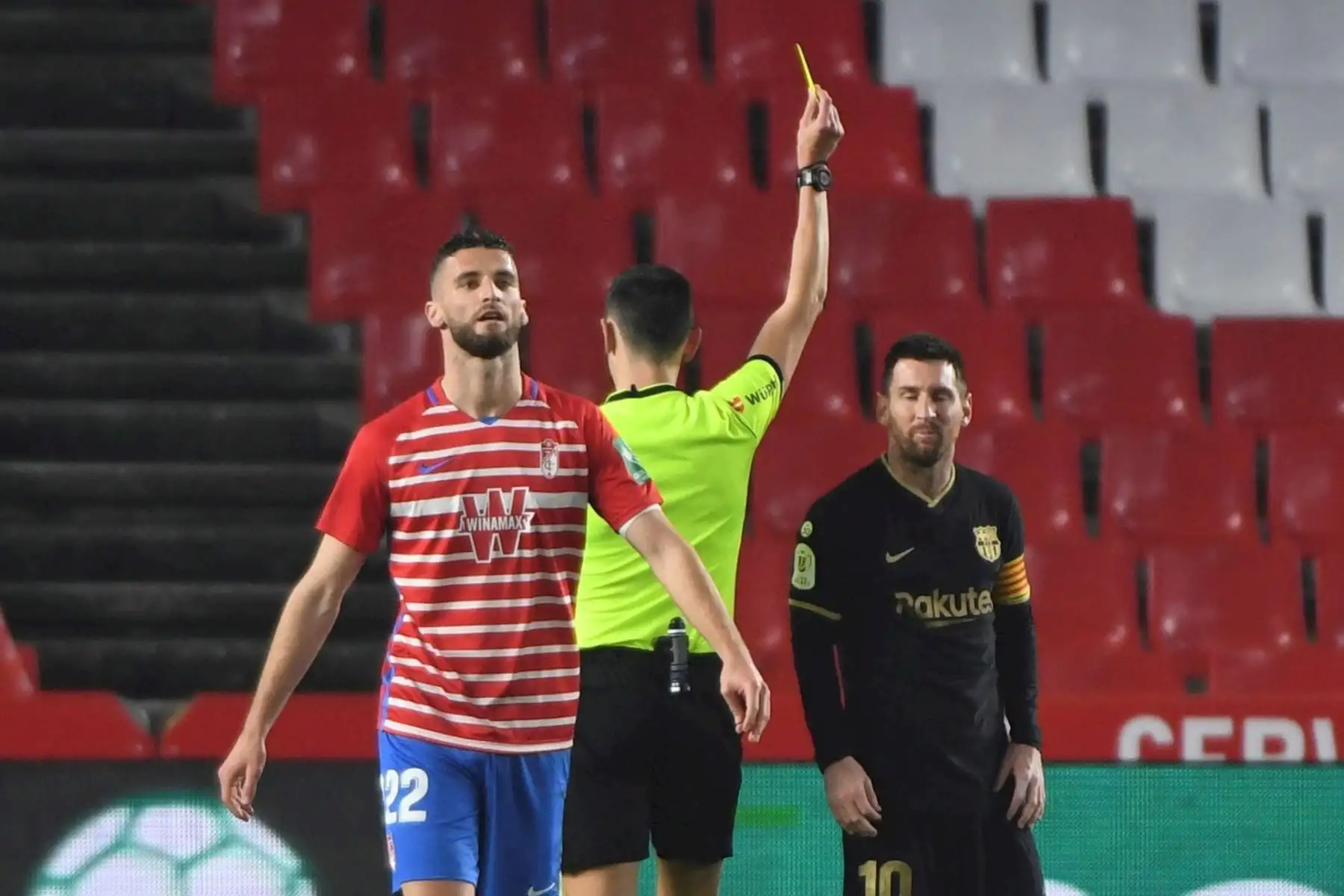 El delantero argentino del FC Barcelona Leo Messi (d) recibe una tarjeta amarilla durante el encuentro de cuartos de final de la Copa del Rey celebrado este miércoles en el estadio Nuevos Los Cármenes, en Granada. 

Foto: EFE