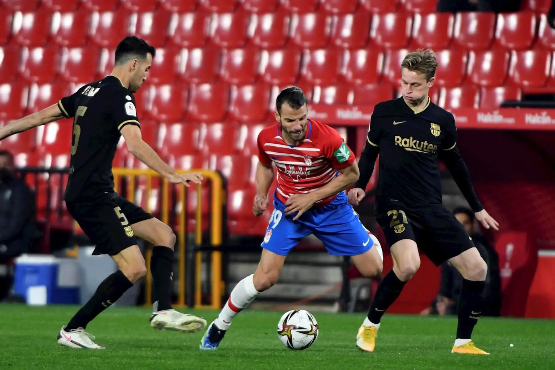 El delantero del Granada, Roberto Soldado (c), disputa un balón con los centrocampistas del FC Barcelona, el español Sergio Busquets (i) y el holandés Frenkie de Jong (d), durante el encuentro de cuartos de final de la Copa del Rey celebrado este miércoles en el estadio Nuevos Los Cármenes, en Granada. 

Foto: EFE