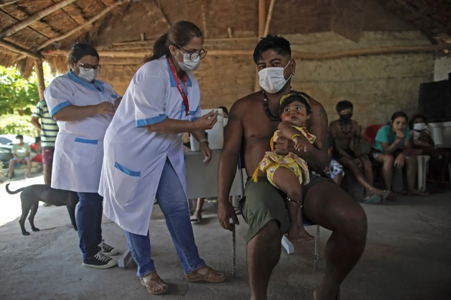 Un indígena guaraní sostiene a su hija mientras es inoculado con CoronaVac de Sinovac Biotech contra el covid-19 en el campamento de la tribu Sao Mata Verde Bonita, en tierra indígena guaraní, en el ciudad de Marica, estado de Río de Janeiro, Brasil. Foto: AFP