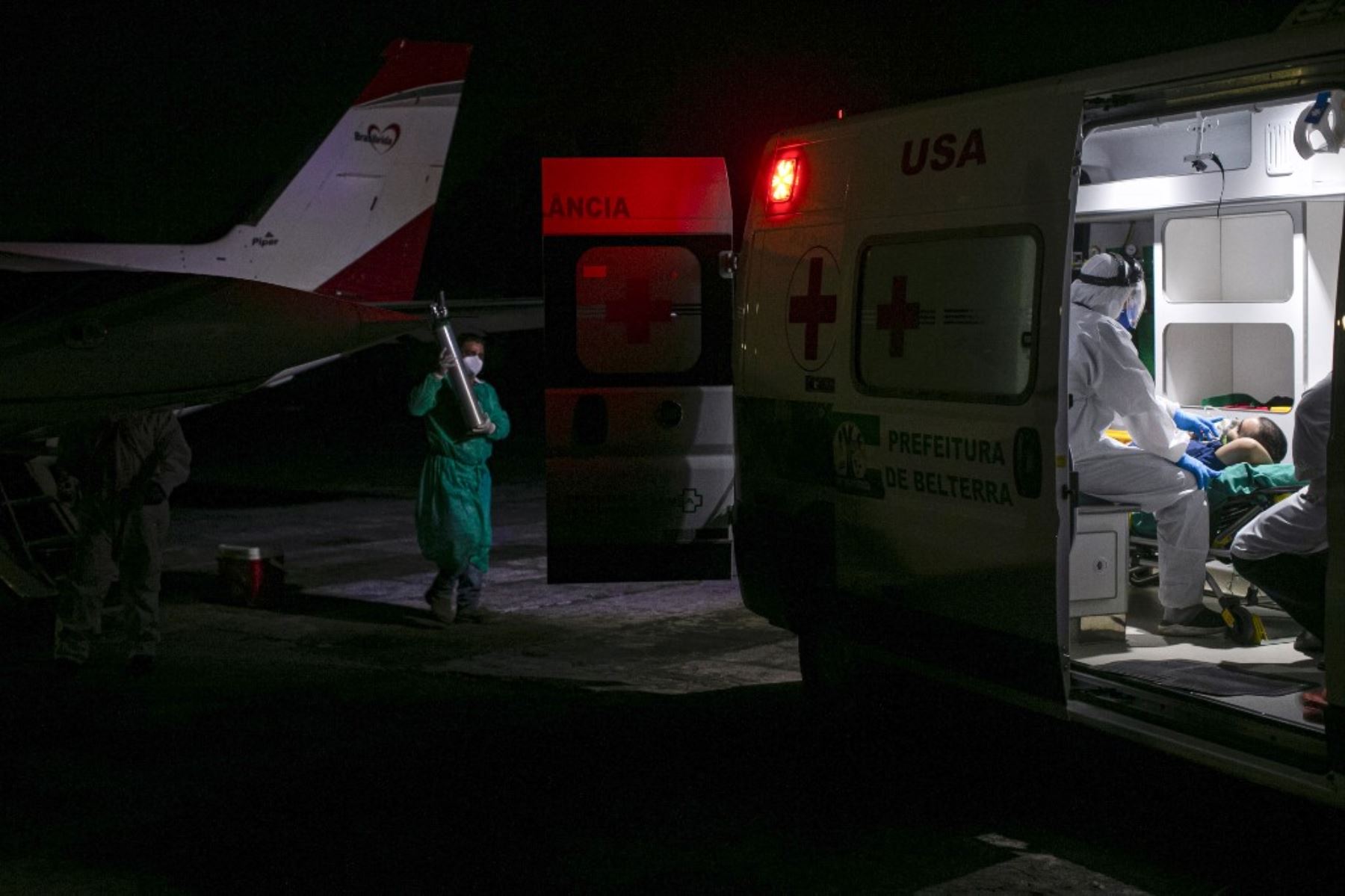 Un trabajador de la salud lleva un cilindro de oxígeno para un paciente de la ciudad de Belterra con covid-19 que llegó en ambulancia al Aeropuerto Internacional Santarem en Santarem, Estado de Pará, Brasil, para ser trasladado en un avión transformado en una unidad de UCI a Itaituba. Foto: AFP