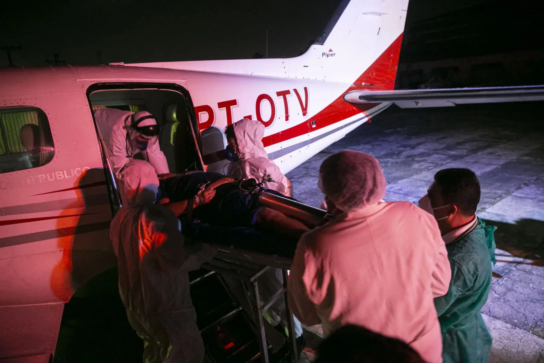 Trabajadores de la salud llevan a un paciente con COVID-19 que llegó en una ambulancia desde la ciudad de Belterra en Santarem, Estado de Pará, Brasil, para ser trasladado en un avión transformado en una unidad de UCI a Itaituba, en el Aeropuerto Internacional de Santarem. Foto: AFP