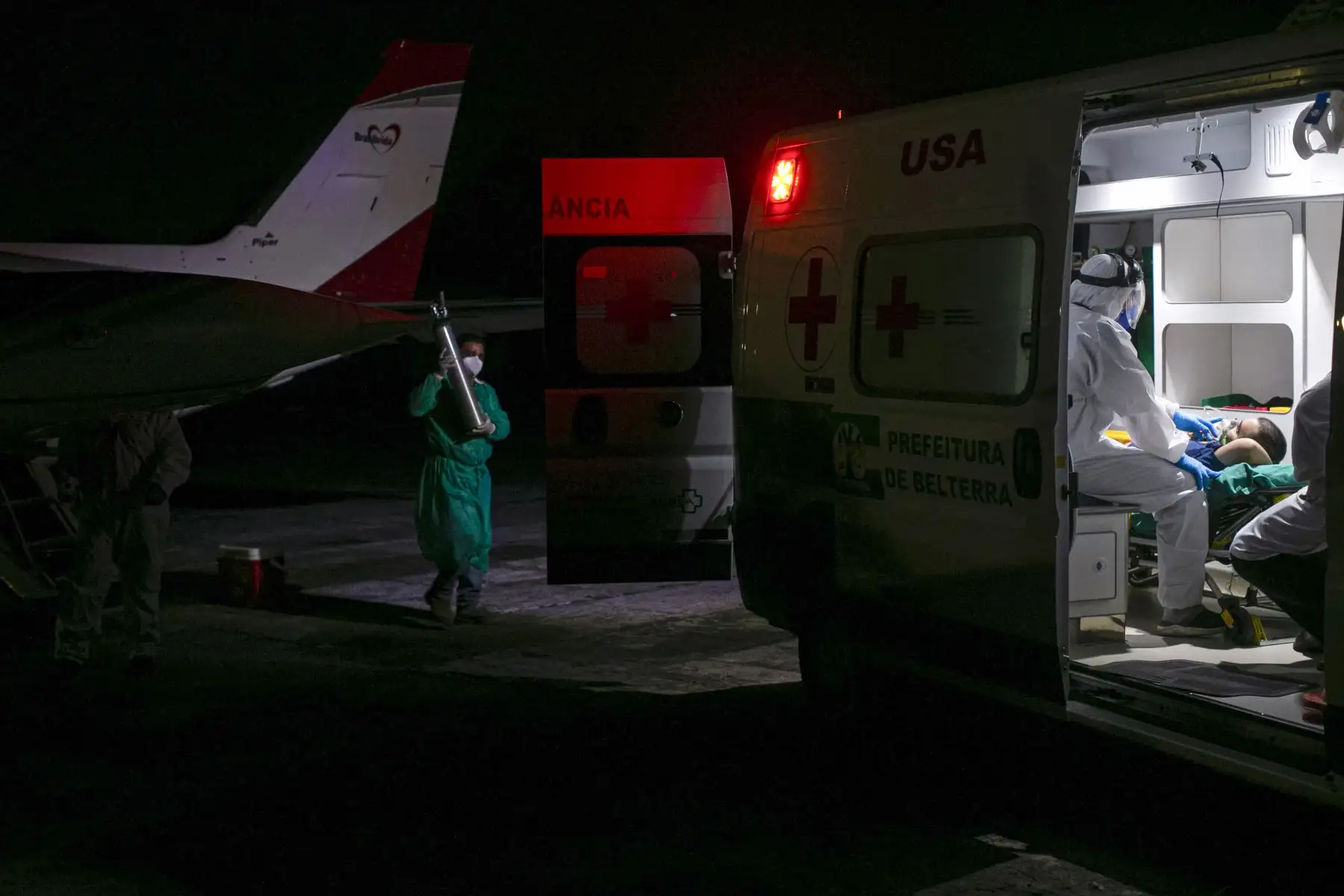 Un trabajador de la salud lleva un cilindro de oxígeno para un paciente de la ciudad de Belterra con COVID-19 que llegó en ambulancia al Aeropuerto Internacional Santarem en Santarem, Estado de Pará, Brasil, para ser trasladado en un avión transformado en una unidad de UCI a Itaituba. Foto: AFP