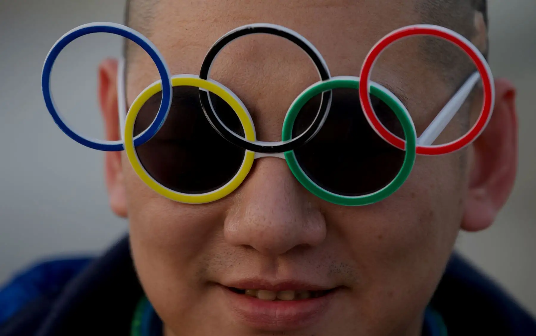 Un hombre lleva gafas de sol de los anillos olímpicos cerca del estadio Birdís Nest, sede de las ceremonias de apertura y clausura de los Juegos Olímpicos de Invierno de 2022, en Beijing. Foto: AFP