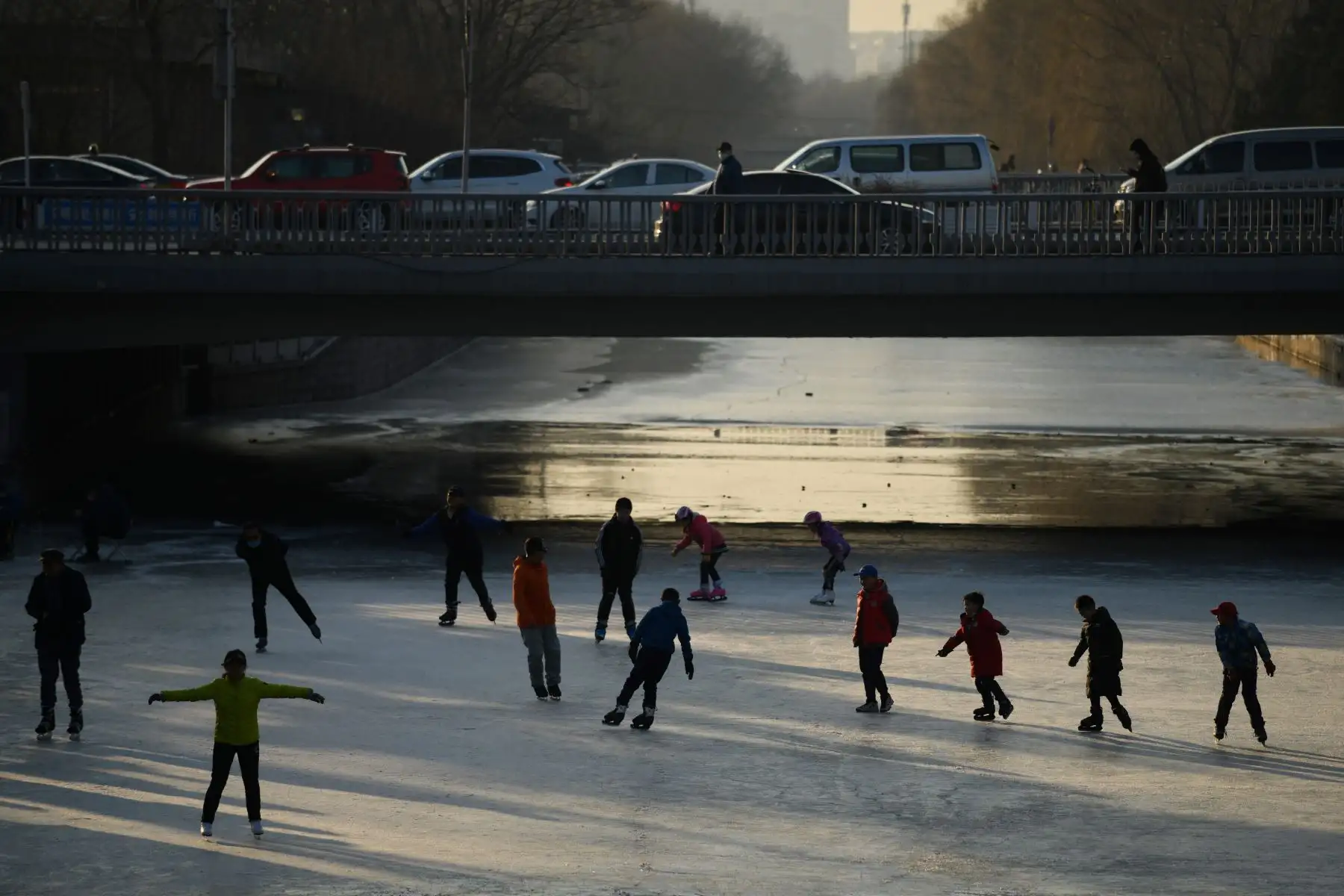 Niños y adultos patinan en un canal helado en Beijing, un año antes de la inauguración de los Juegos Olímpicos de Invierno que se celebrarán en Beijing del 4 al 20 de febrero de 2022.