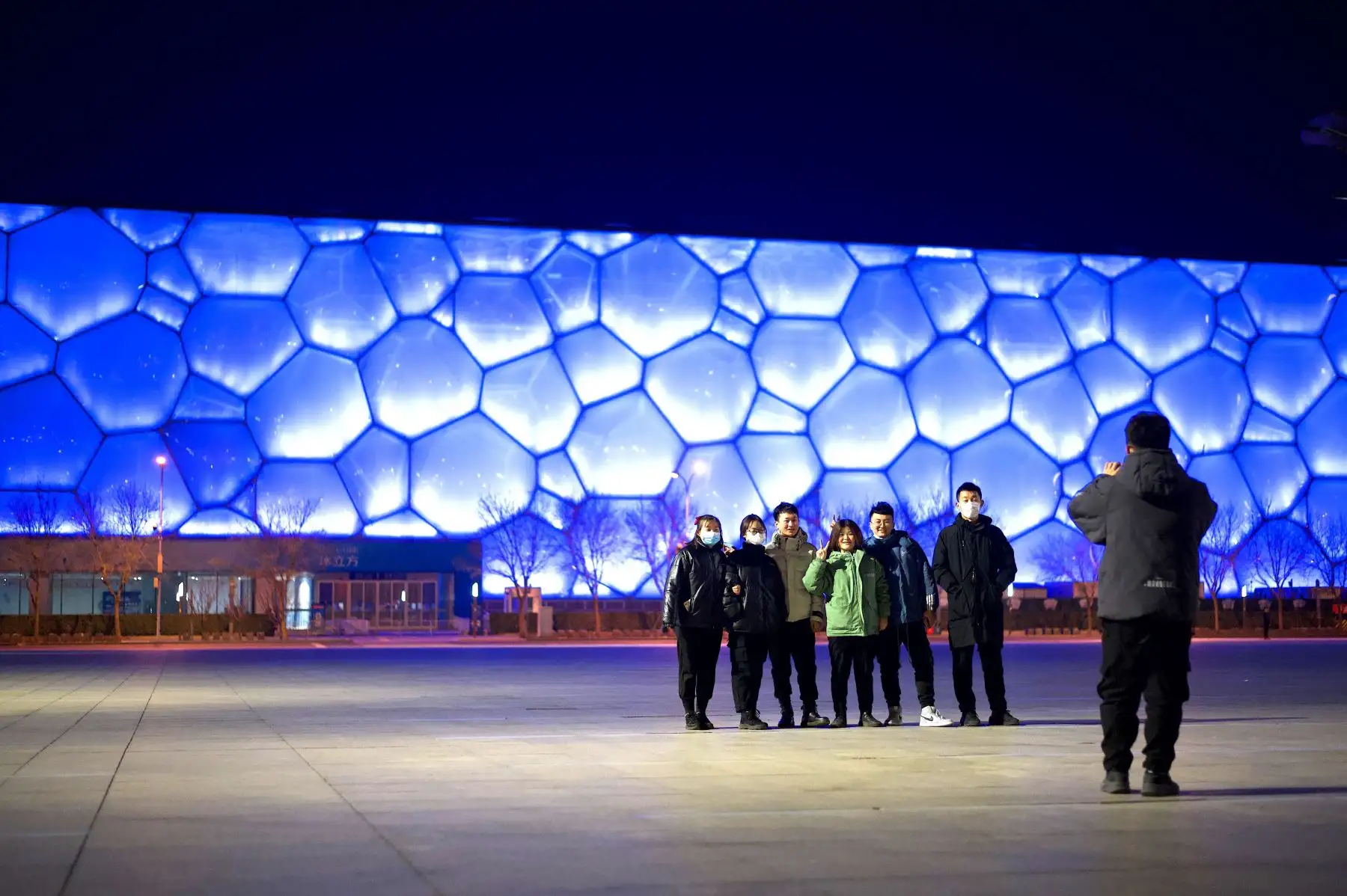 La gente posa para una foto frente al Centro Acuático Nacional, conocido como el Cubo de Agua, que se convertirá en sede de la competencia de curling en los Juegos Olímpicos de Invierno de 2022. Foto: AFP