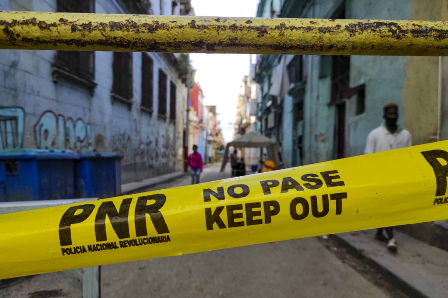 La gente camina cerca de una zona acordonada por la policía por presentar casos de covid-19, en La Habana. Foto: AFP