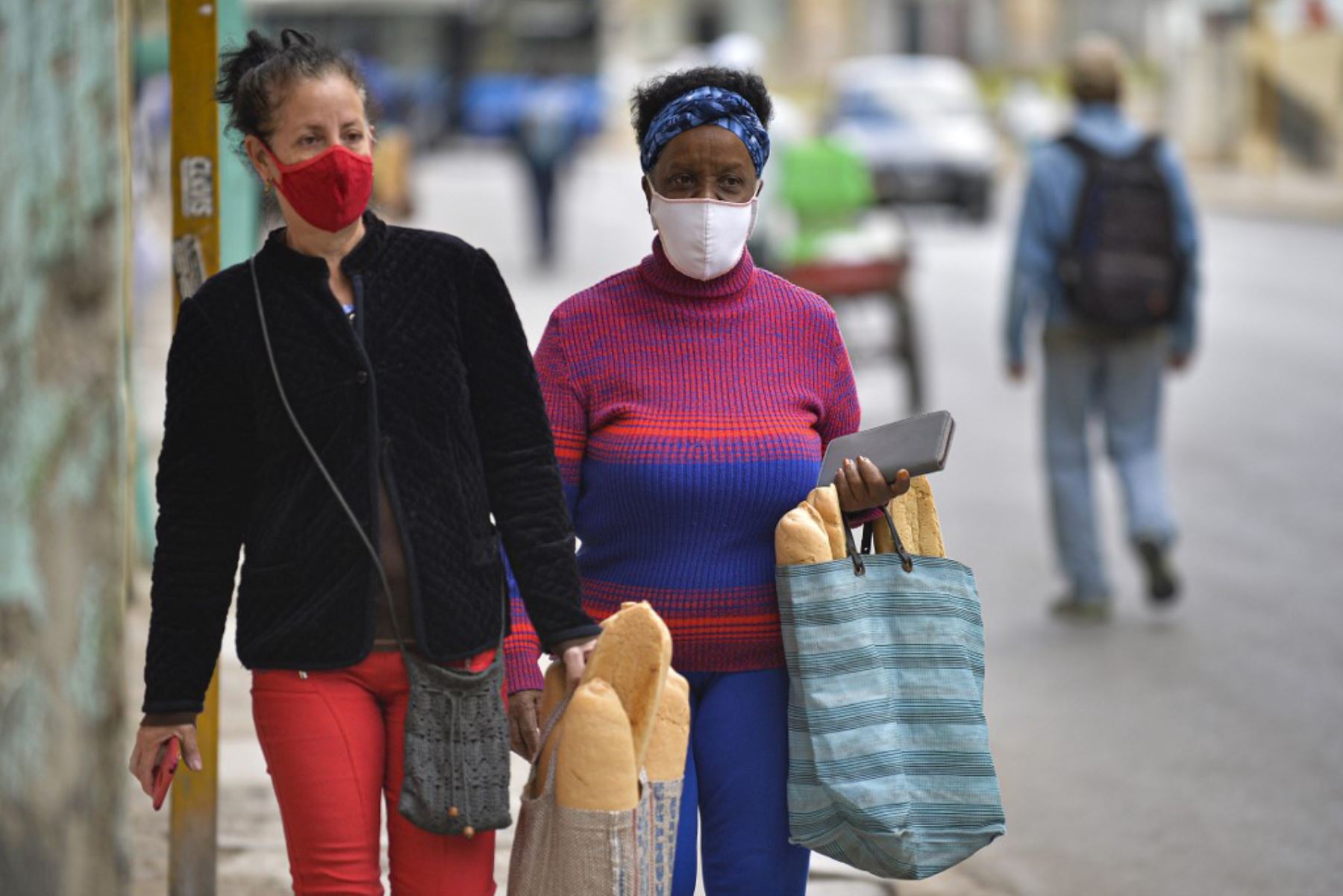 Las mujeres usan máscaras faciales mientras caminan después de comprar pan en La Habana, mientras aumentan los casos de covid-19 en la nación isleña. Foto: AFP